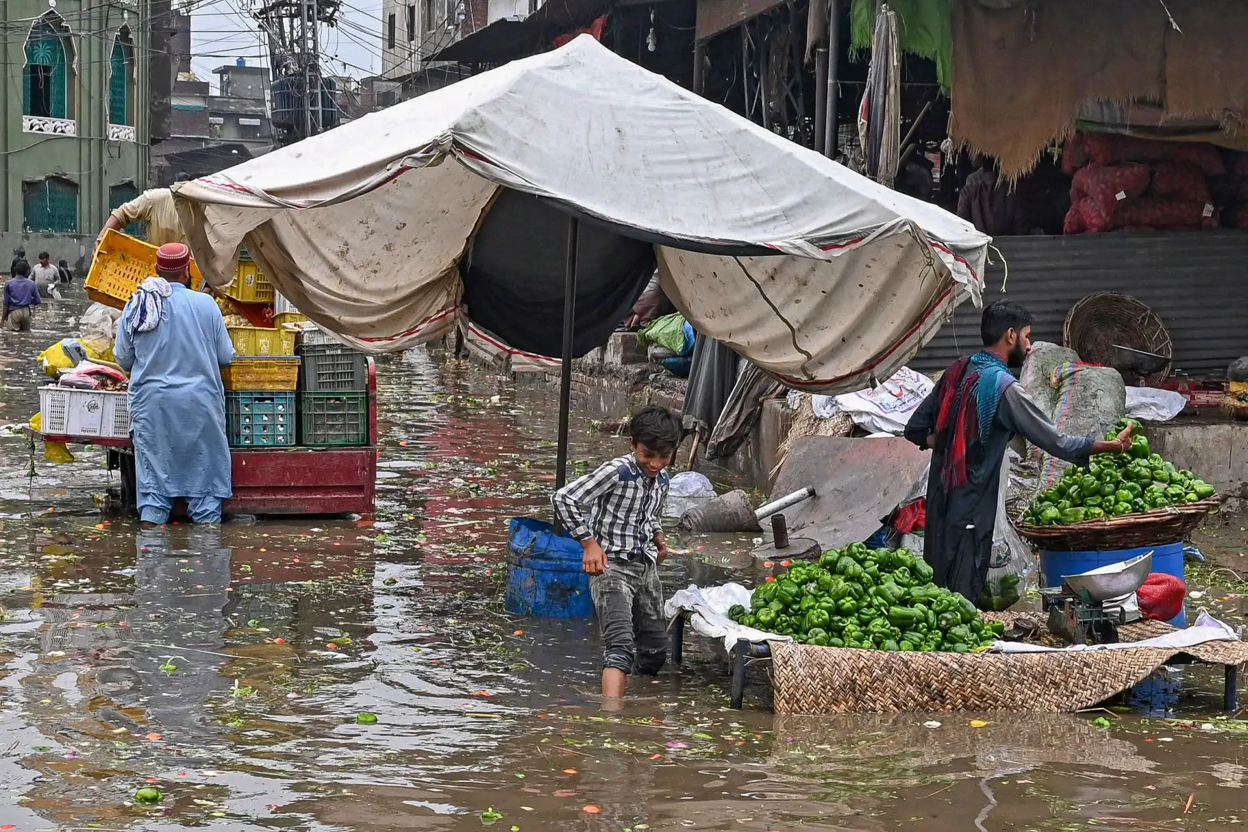 Un niño camina por un mercado inundado después de fuertes lluvias en Lahore.
Foto: AFP