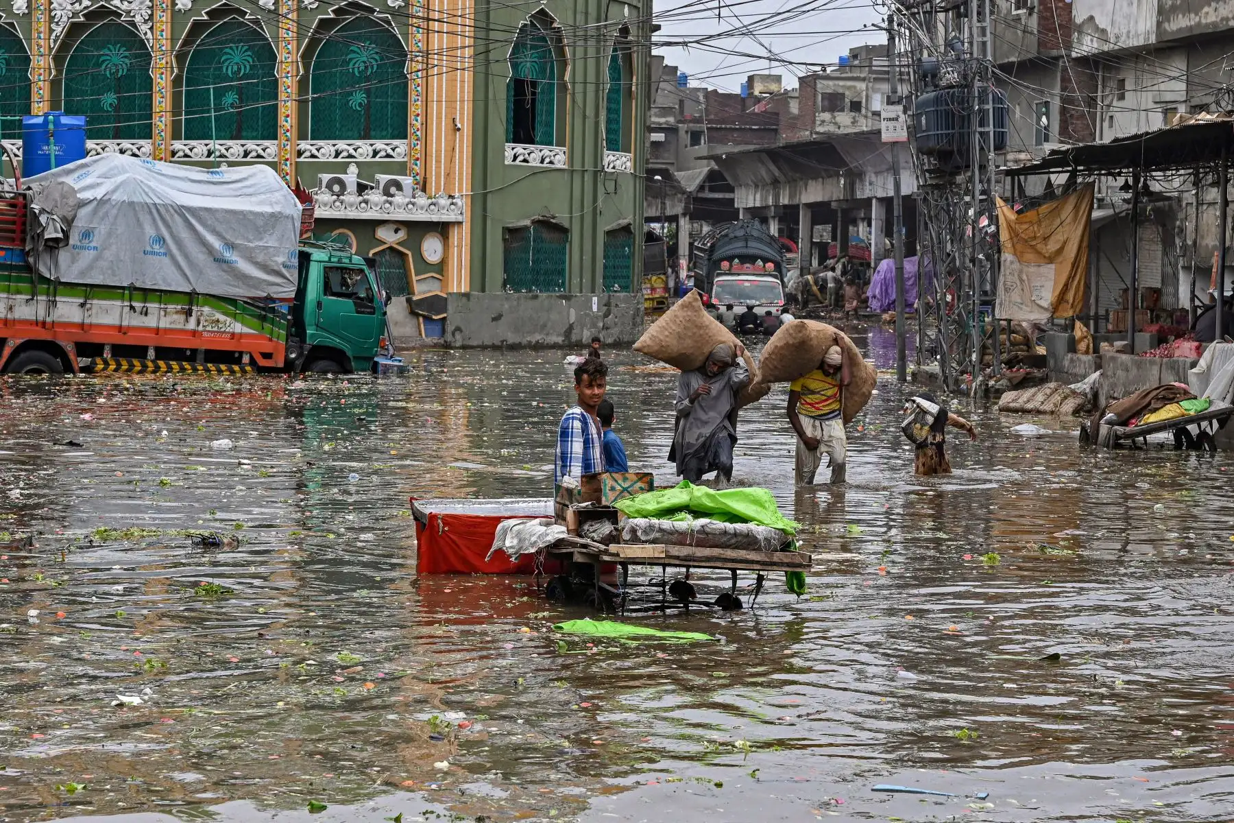 Las personas cargan sacos de verduras mientras caminan por un mercado inundado después de fuertes lluvias en Lahore.
Foto: AFP