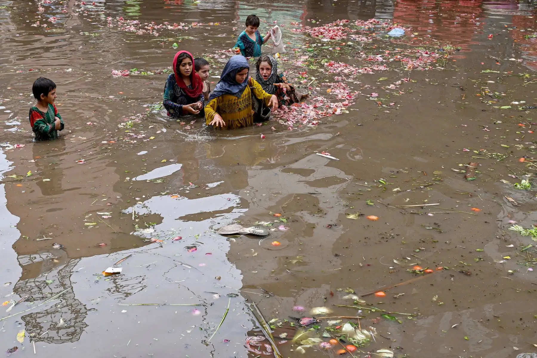 Las personas cargan sacos de verduras mientras caminan por un mercado inundado después de fuertes lluvias en Lahore.
Foto: AFP