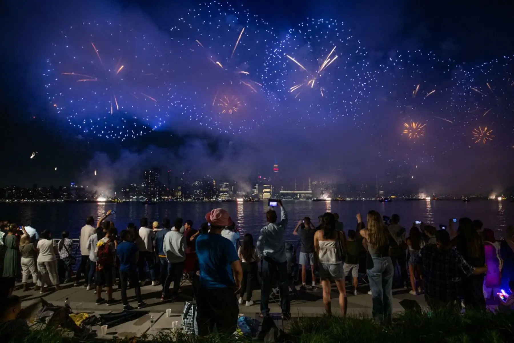 La gente observa cómo estallan los fuegos artificiales sobre el horizonte de Manhattan durante la exhibición de fuegos artificiales del Día de la Independencia de Macy