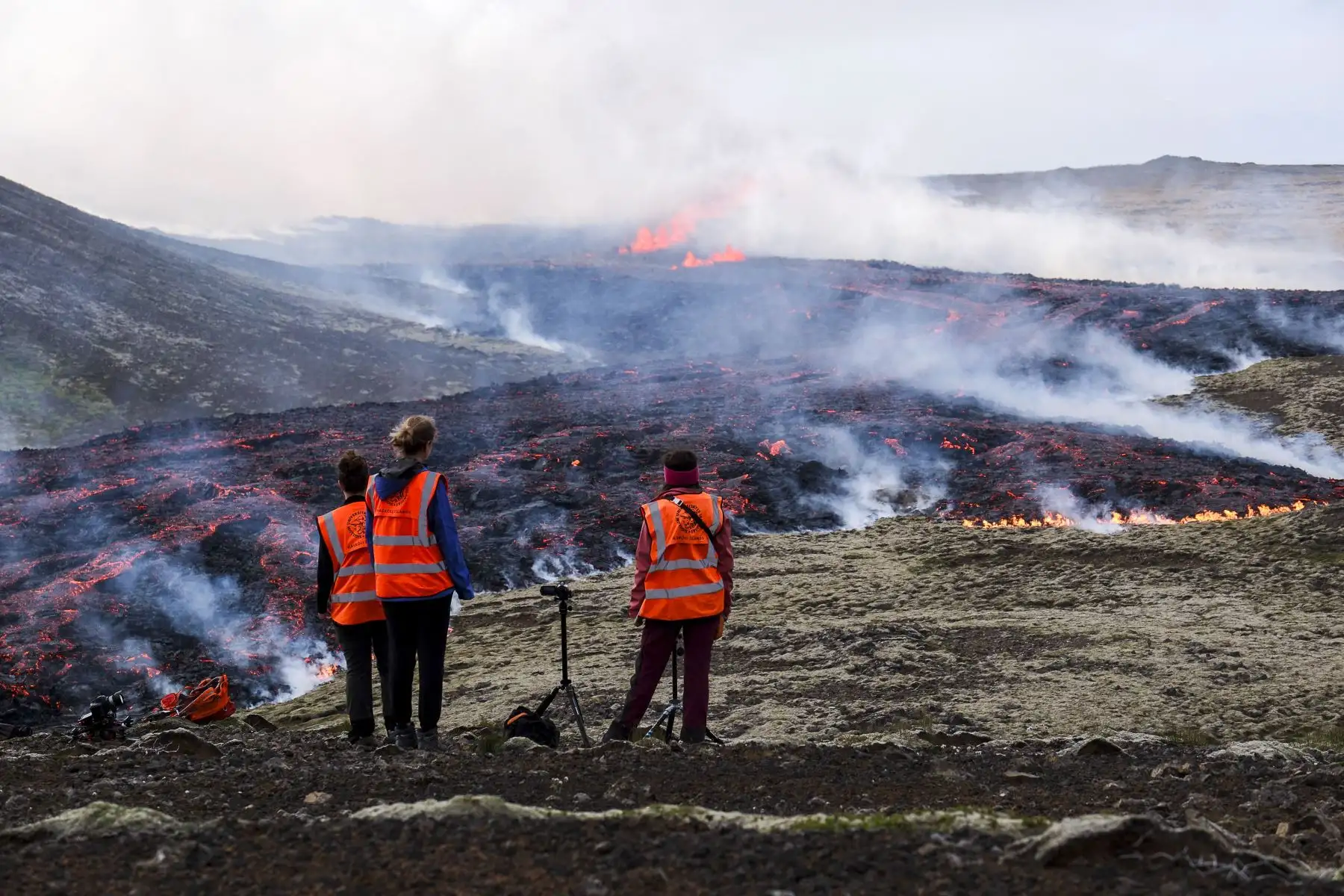 Los observadores de la Universidad de Islandia se paran frente al humo que sale de la lava que fluye durante una erupción volcánica cerca de Litli Hrutur, al suroeste de Reykjavik en Islandia el 10 de julio de 2023. 
Foto: AFP