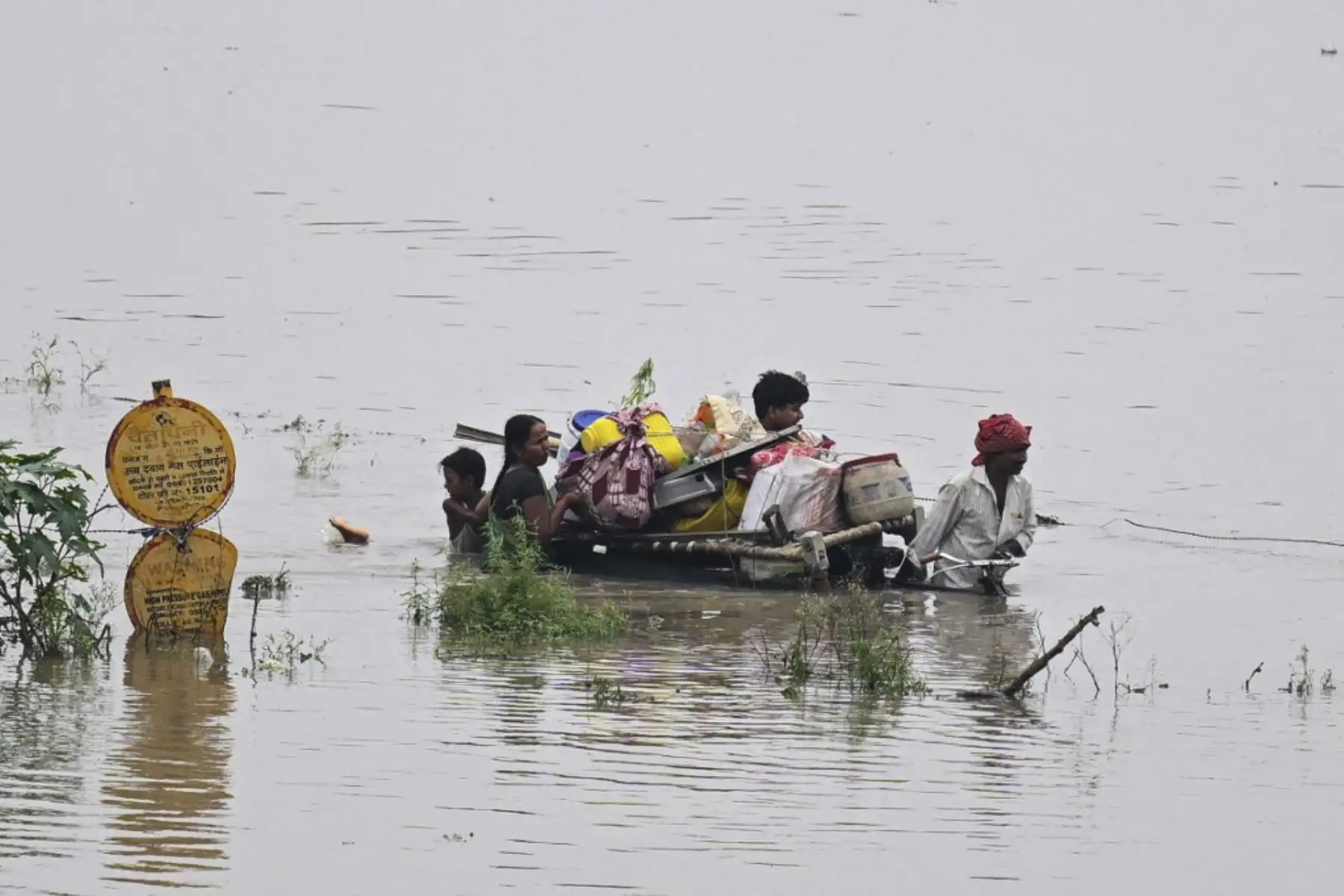 Una familia empuja un carrito de bicicletas cargado con sus pertenencias en una zona baja inundada cerca del río Yamuna después de que se desbordara debido a las lluvias monzónicas en Nueva Delhi. Foto: AFP