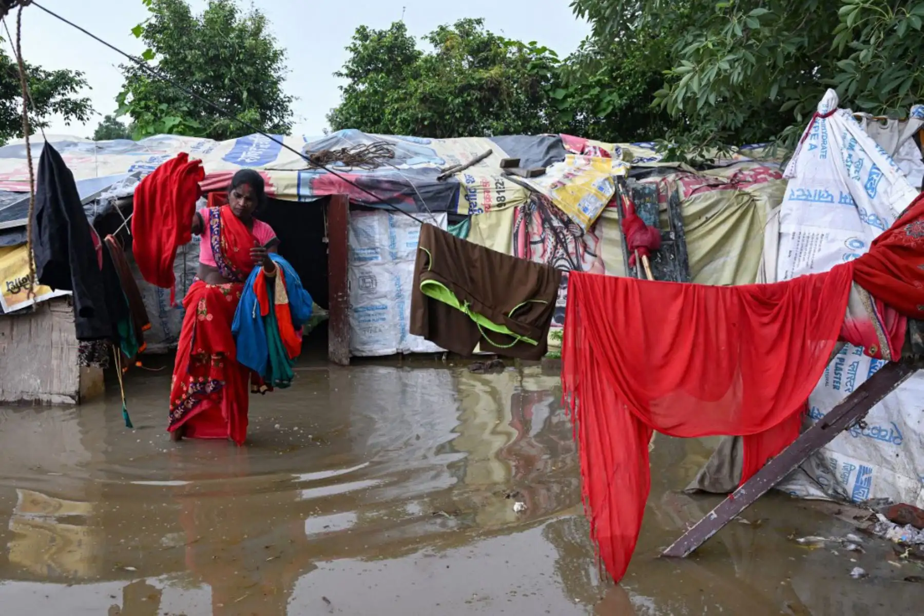 Una mujer recoge sus pertenencias antes de trasladarse desde un área baja cerca del río Yamuna después de que se desbordara debido a las lluvias monzónicas, en Nueva Delhi. Foto: AFP