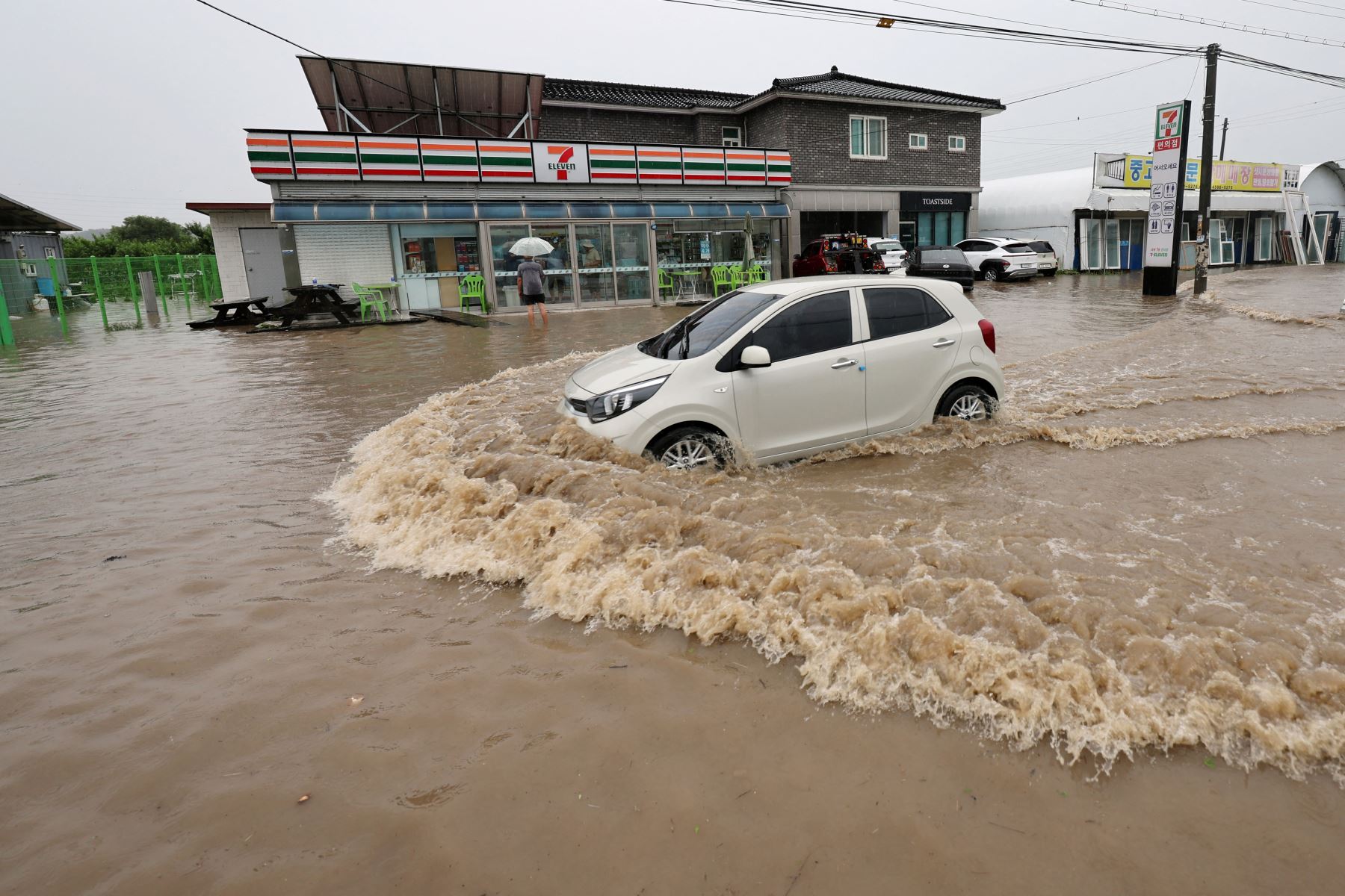 Un automóvil circula por una carretera inundada por las fuertes lluvias en Cheongju el 15 de julio de 2023. Al menos 22 personas han muerto y 14 más están desaparecidas después de que las fuertes lluvias provocaron inundaciones y deslizamientos de tierra en Corea del Sur, dijeron las autoridades el 15 de julio, y se ordenaron miles más. para evacuar sus casas. Foto: AFP