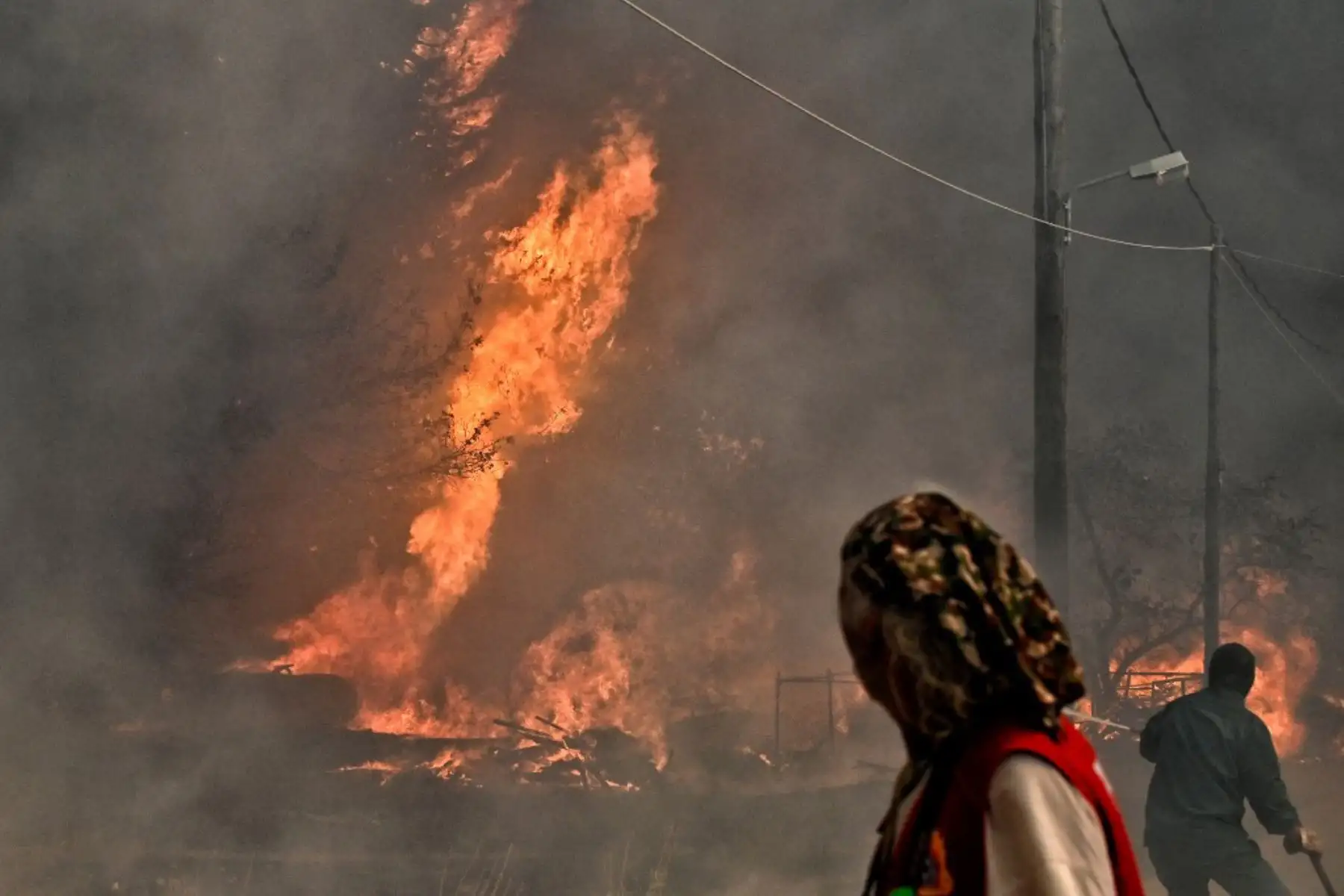Los residentes locales observan el incendio forestal que se desató en el asentamiento de Irini, cerca de la ciudad turística de Loutraki, a unos 80 kilómetros al este de Atenas. Foto: AFP