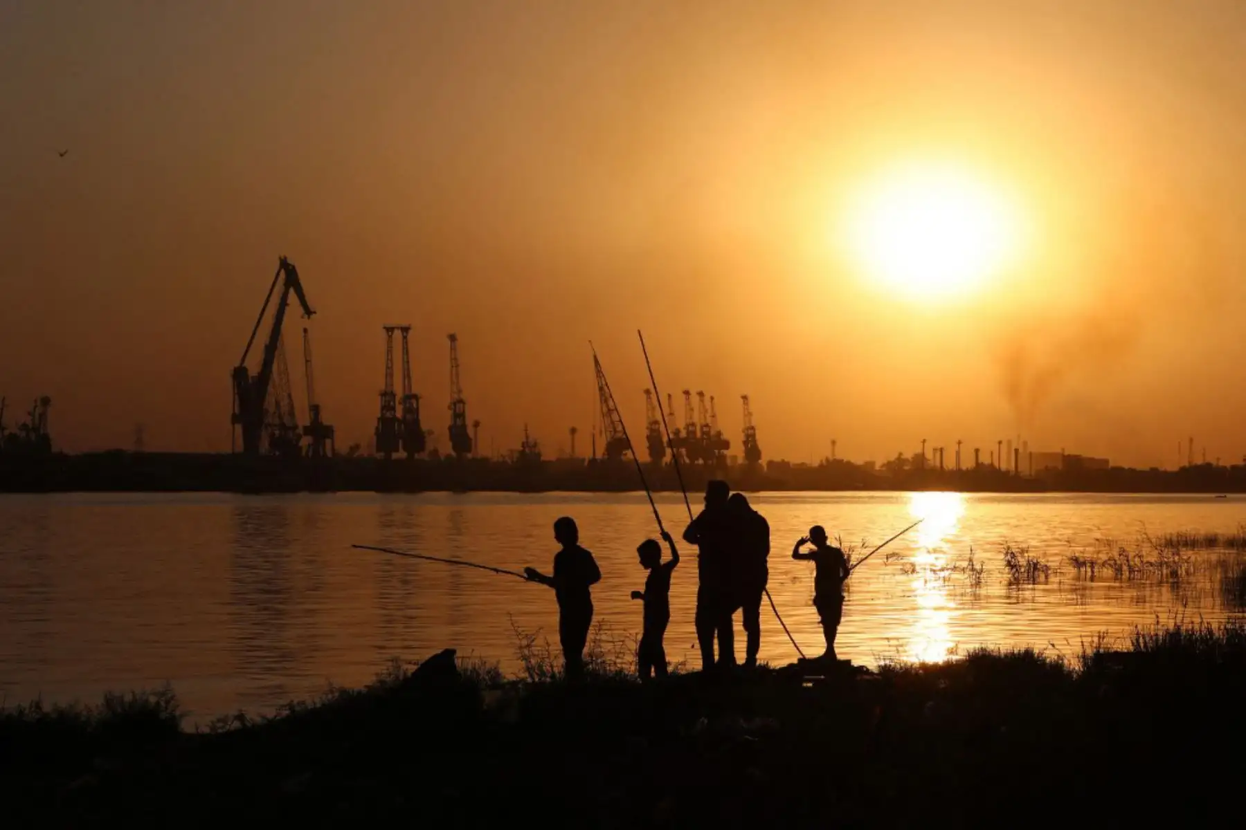 La gente pesca con cañas en el canal Shatt al-Arab en la ciudad de Basora, en el sur de Irak. Foto: AFP