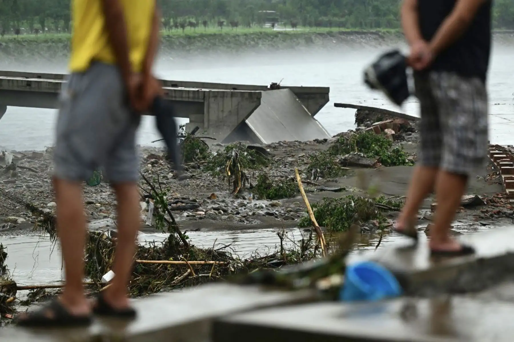 La gente observa un puente derrumbado en el río Dashihe después de fuertes lluvias en el distrito de Fangshan en Beijing. Al menos 20 personas murieron y 19 desaparecieron después de que las fuertes lluvias azotaran Beijing, dijeron los medios estatales el 1 de agosto, en aguaceros que han carreteras sumergidas y barrios inundados de lodo. Foto: AFP