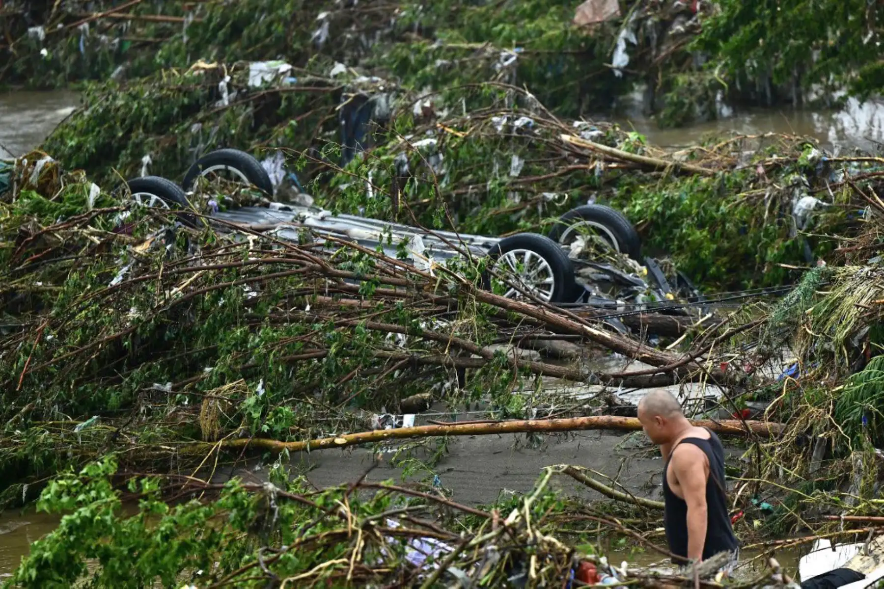 Un hombre mira un automóvil volcado luego de las fuertes lluvias en el distrito de Fangshan en Beijing. Al menos 20 personas murieron y 19 desaparecieron después de que las fuertes lluvias azotaran Beijing, dijeron los medios estatales el 1 de agosto, en aguaceros que han sumergido las carreteras. y barrios inundados de lodo.Foto: AFP