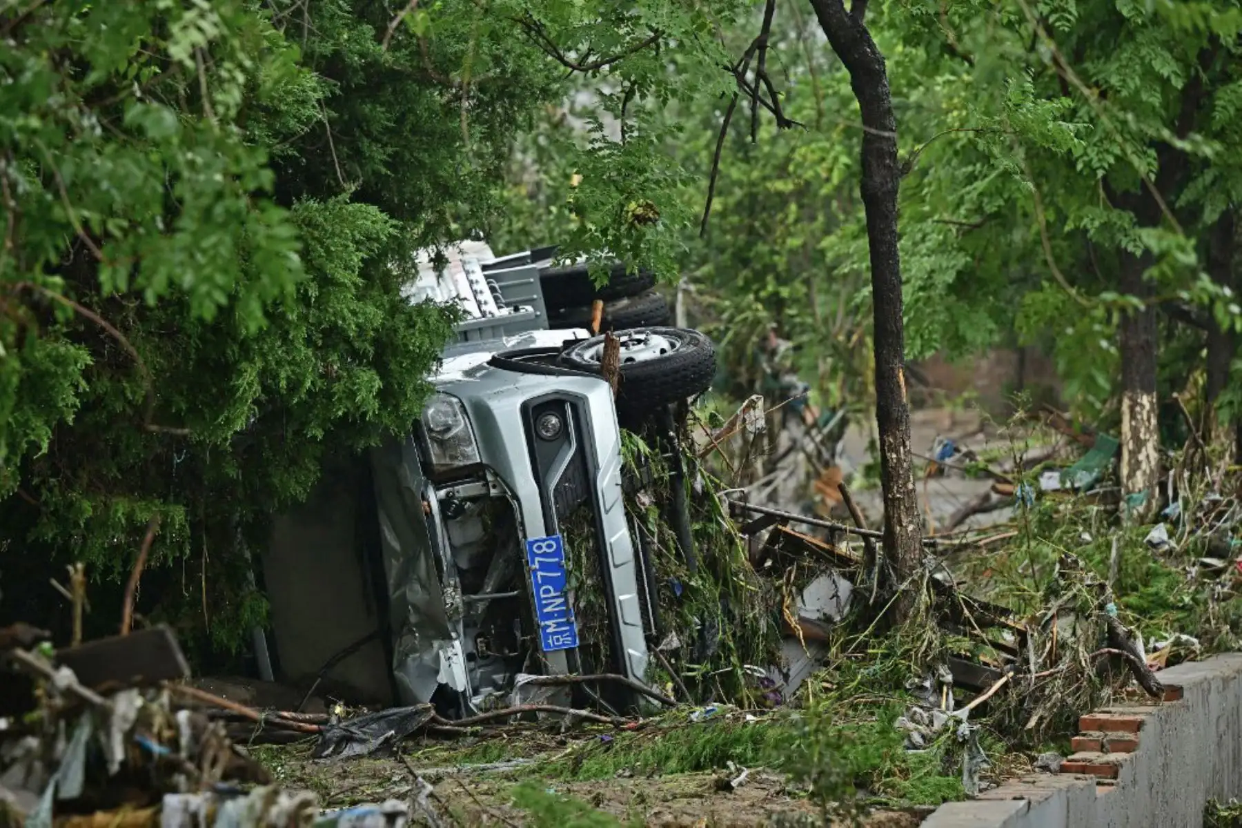 Se muestra un automóvil volcado a lo largo de una calle después de las fuertes lluvias en el distrito de Fangshan en Beijing. Al menos 20 personas murieron y 19 desaparecieron después de que las fuertes lluvias azotaran Beijing, dijeron los medios estatales el 1 de agosto, en aguaceros que han sumergido carreteras y barrios inundados de lodo. Foto: AFP