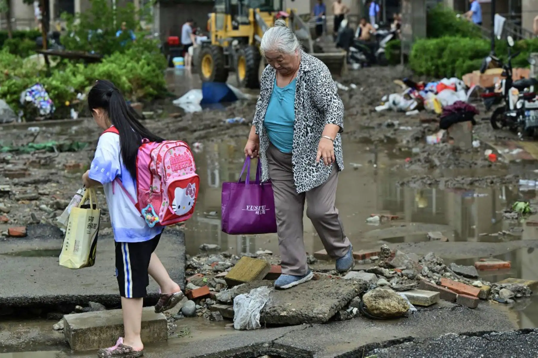 La gente se abre paso a través de una carretera dañada luego de las fuertes lluvias en el distrito de Fangshan en Beijing. Al menos 20 personas murieron y 19 desaparecieron después de que las fuertes lluvias azotaran Beijing, dijeron los medios estatales. Foto: AFP