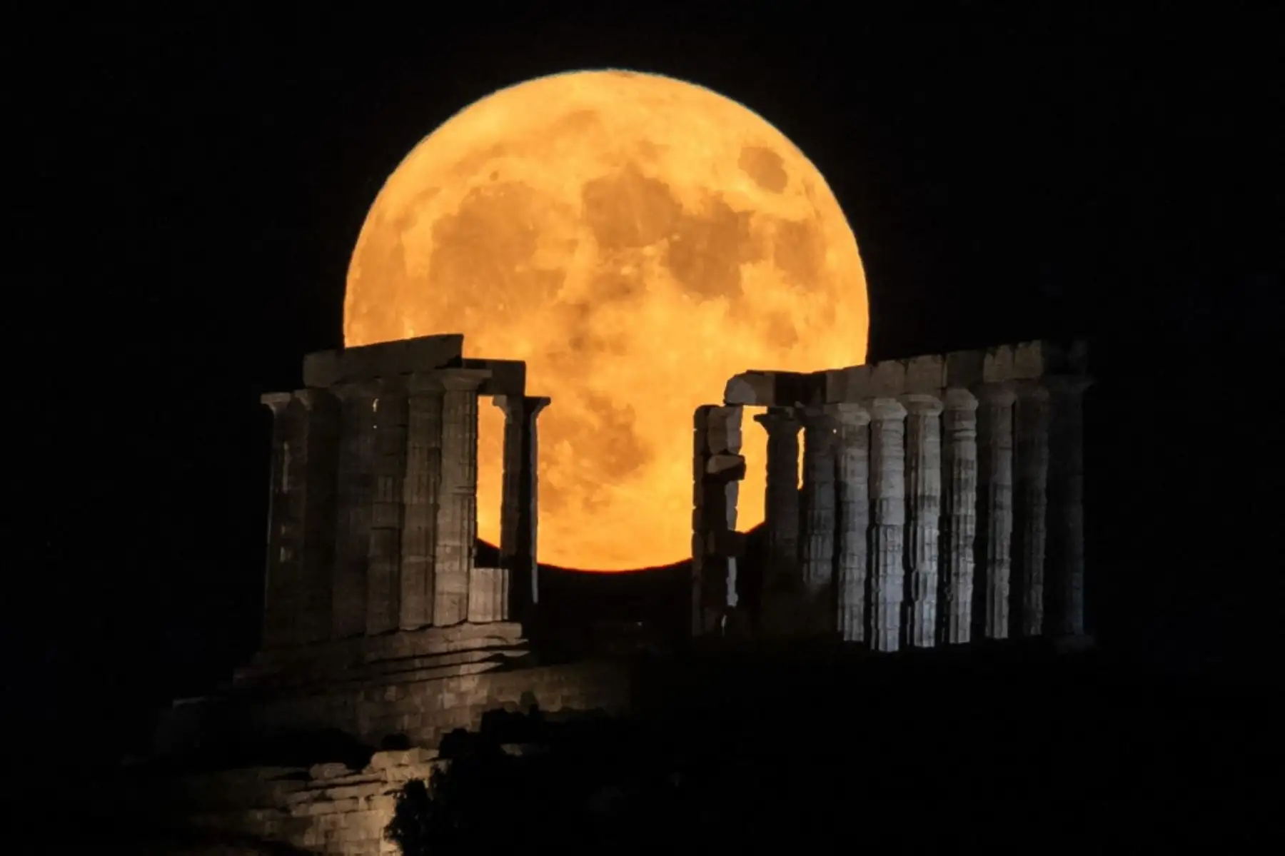 La luna llena se eleva detrás del antiguo templo de Poseidón en el cabo Sounion, al sur de Atenas. Foto: AFP