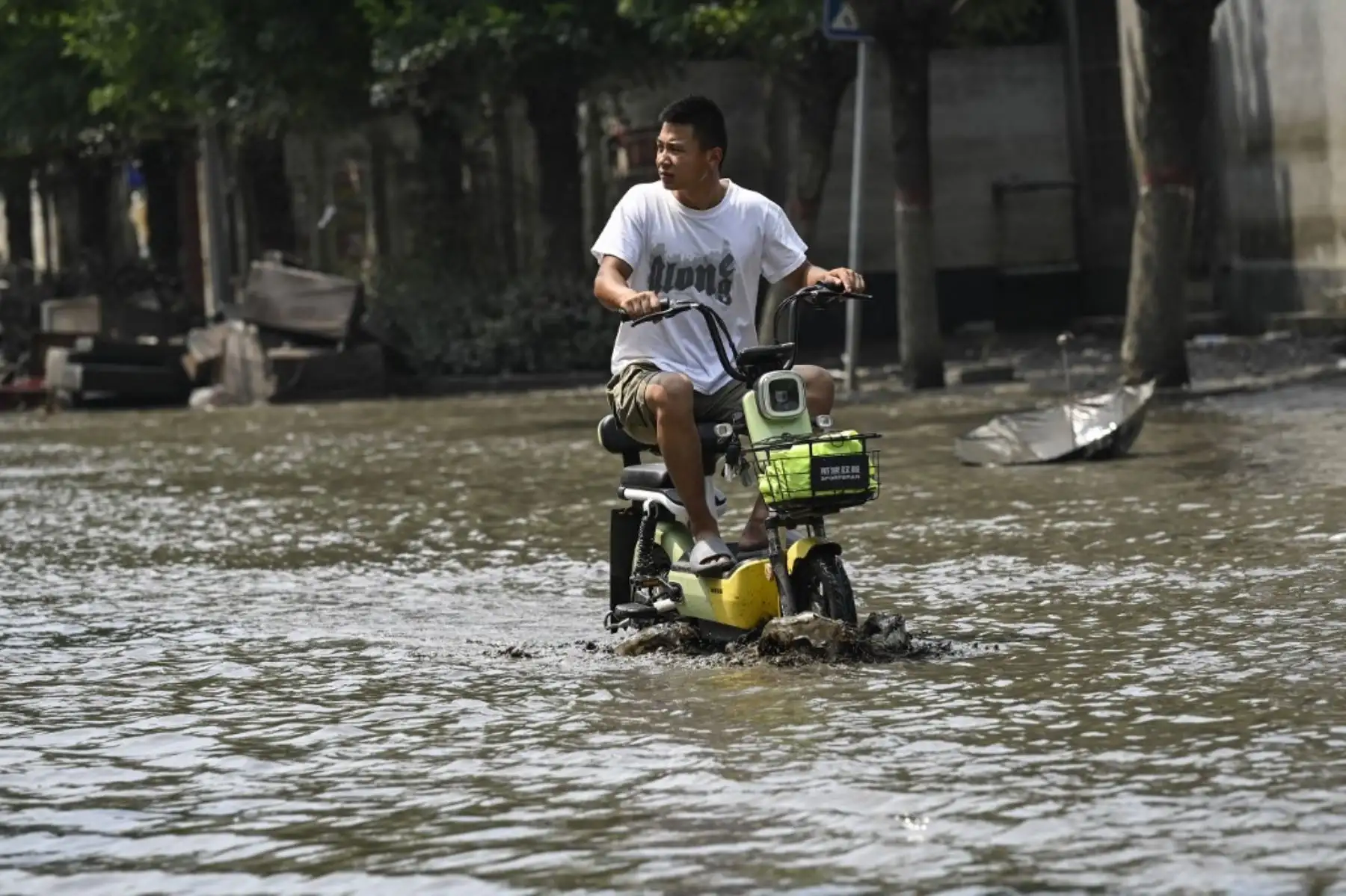 Los residentes locales viajan en scooter por una calle embarrada después de las inundaciones provocadas por las fuertes lluvias en la ciudad de Zhuozhou, en la provincia de Hebei, en el norte de China. Foto: AFP