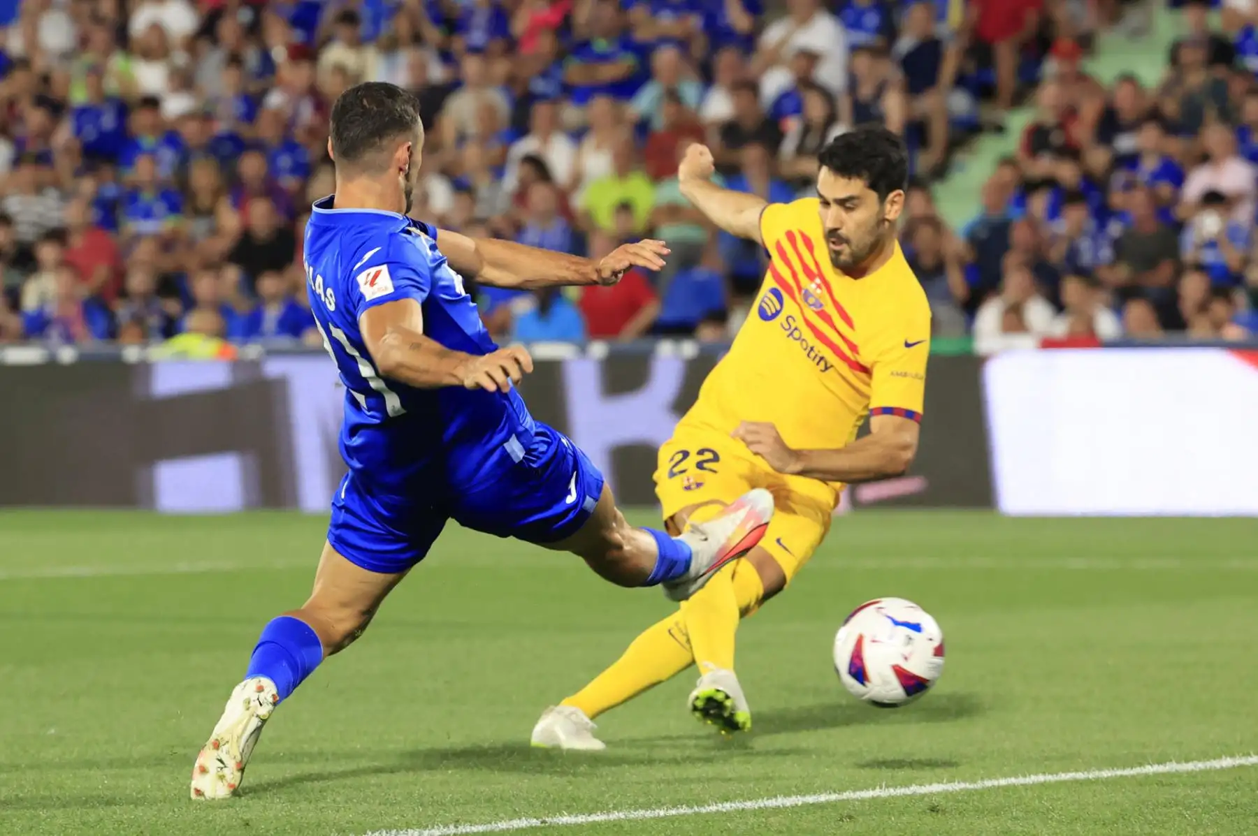 El centocampista del FC Barcelona Ilkay Gündogan (d) juega un balón ante Juan Iglesias, del Getafe, durante el partido de la primera jornada de LaLiga que disputan este domingo en el Coliseum Alfonso Pérez. Foto: EFE