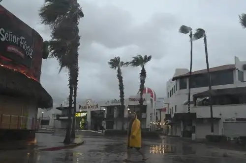 Un hombre camina por una calle en Cabo San Lucas, estado de Baja California, México, mientras la lluvia y las ráfagas de viento del huracán Hilary llegan a la zona, el 19 de agosto de 2023. Foto: AFP