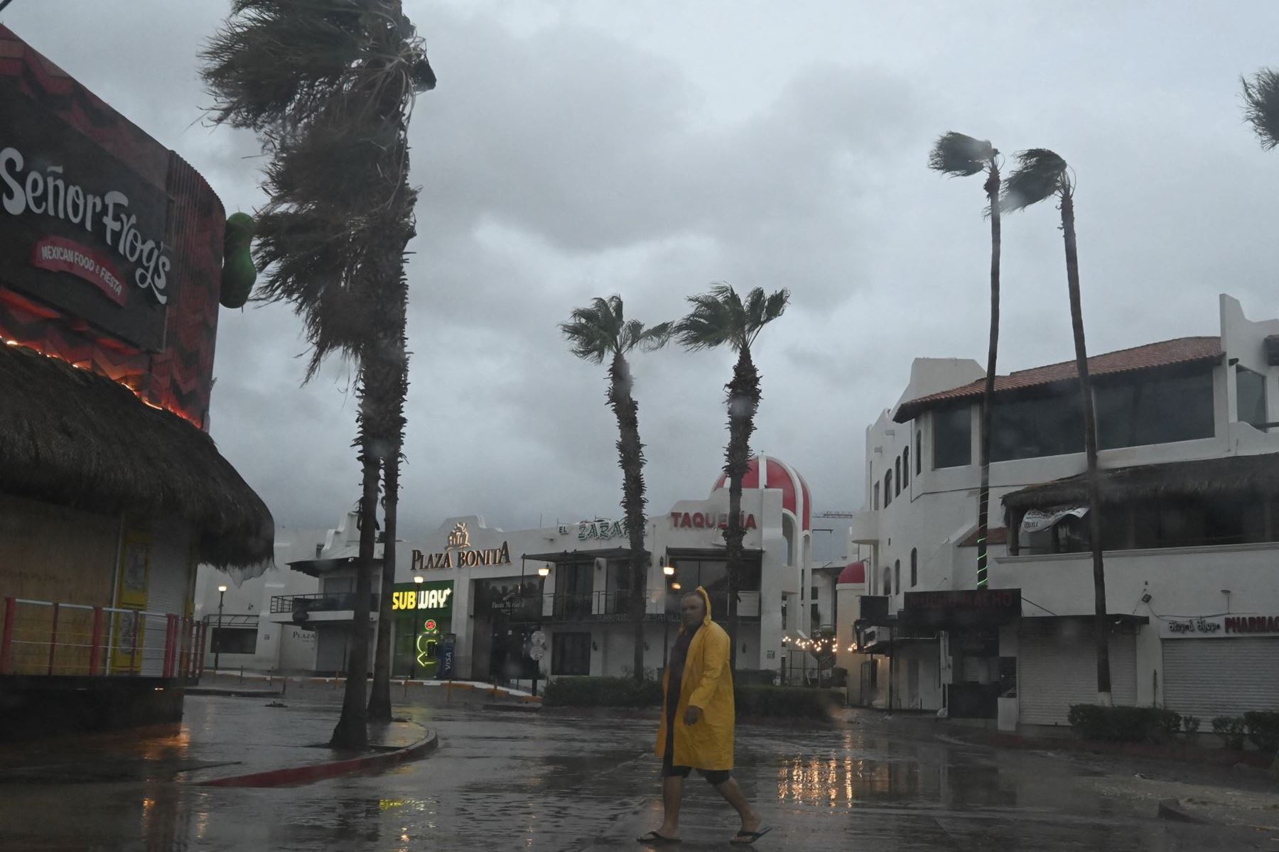 Un hombre camina por una calle en Cabo San Lucas, estado de Baja California, México, mientras la lluvia y las ráfagas de viento del huracán Hilary llegan a la zona, el 19 de agosto de 2023. Foto: AFP