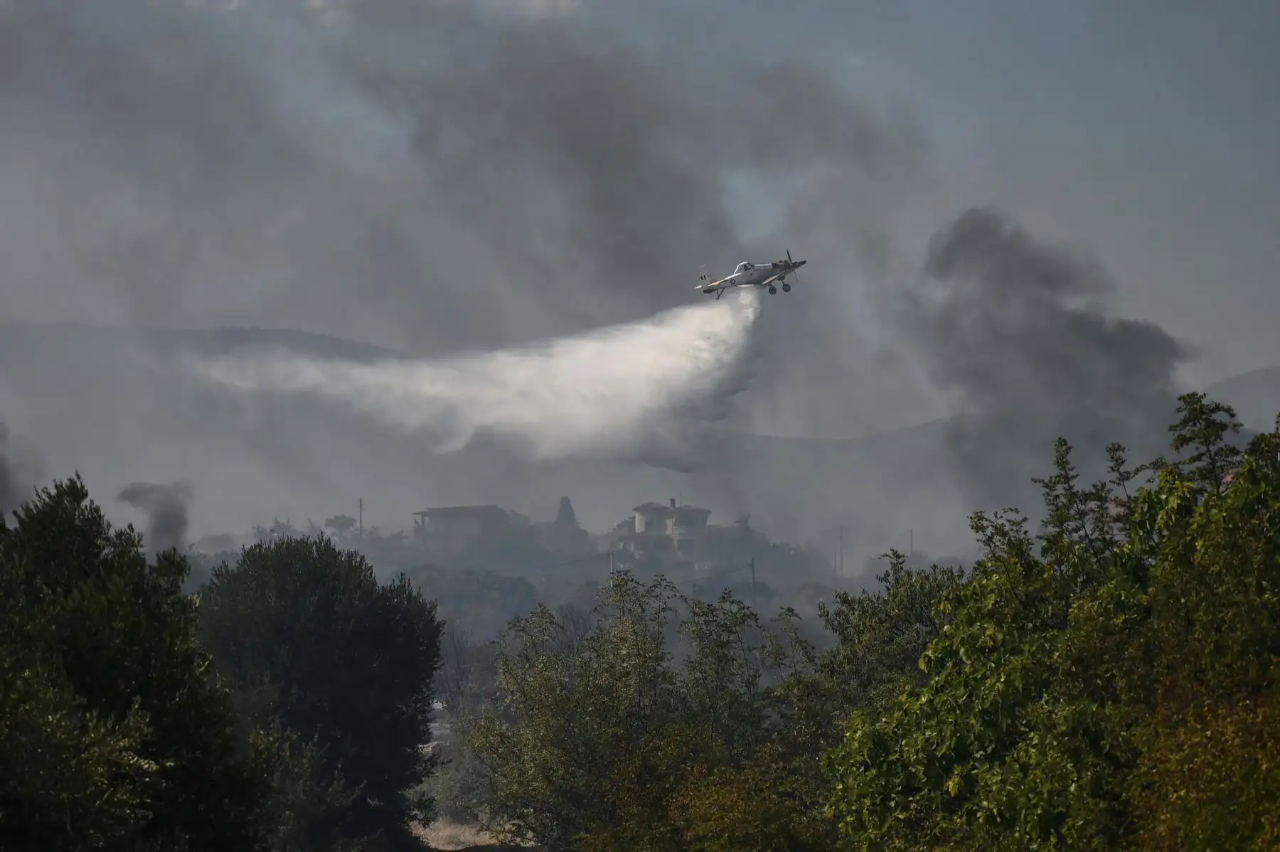 Un avión de extinción de incendios rocía agua mientras sobrevuela la aldea de Dialekto cerca de Kavala, en el norte de Grecia. Foto:ANDINA/AFP