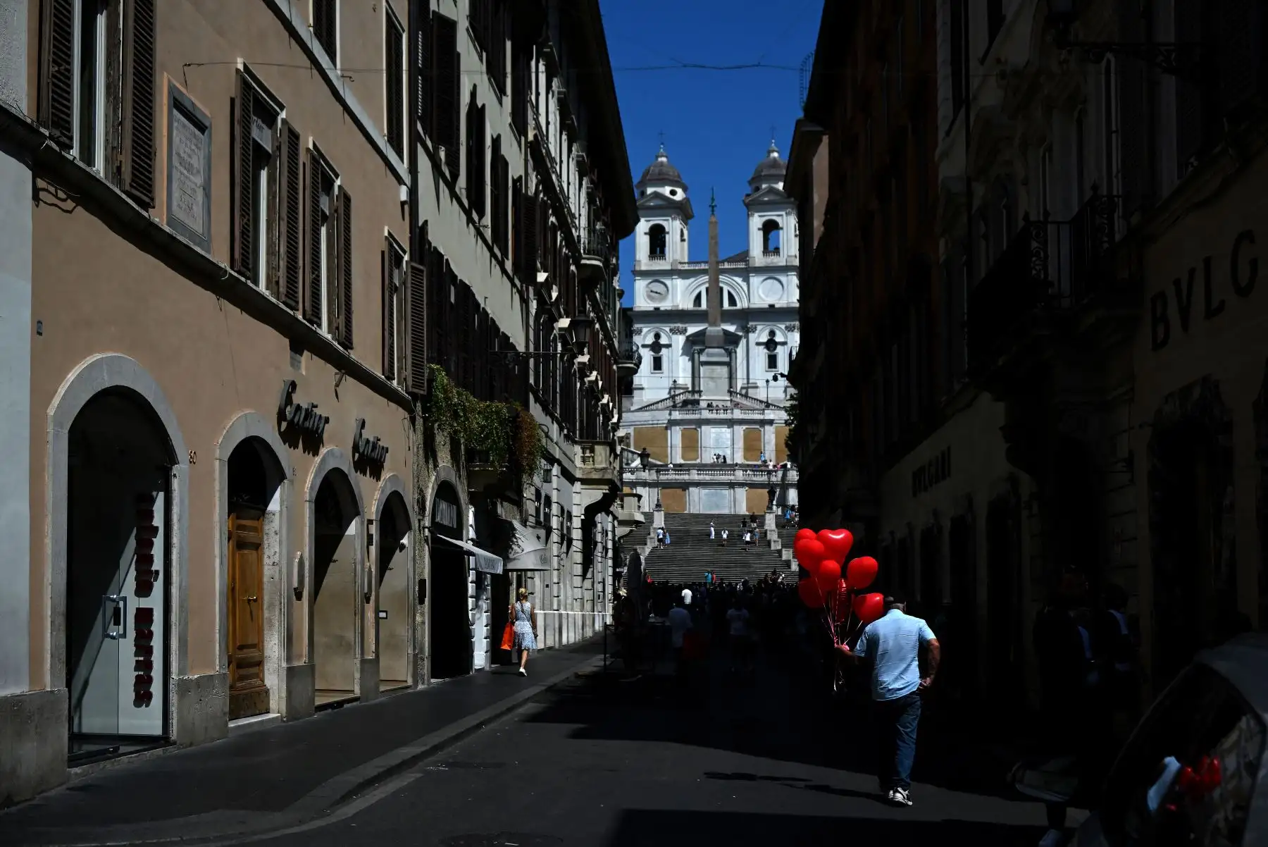 Un vendedor ambulante sostiene globos en forma de corazón mientras camina en dirección a la iglesia católica Trinta dei Monti durante una ola de calor en Roma. Foto:ANDINA/AFP