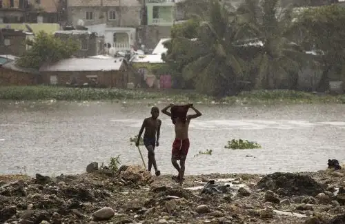 Niños juegan bajo las primeras lluvias que trae la tormenta tropical Franklin, hoy en Santo Domingo.