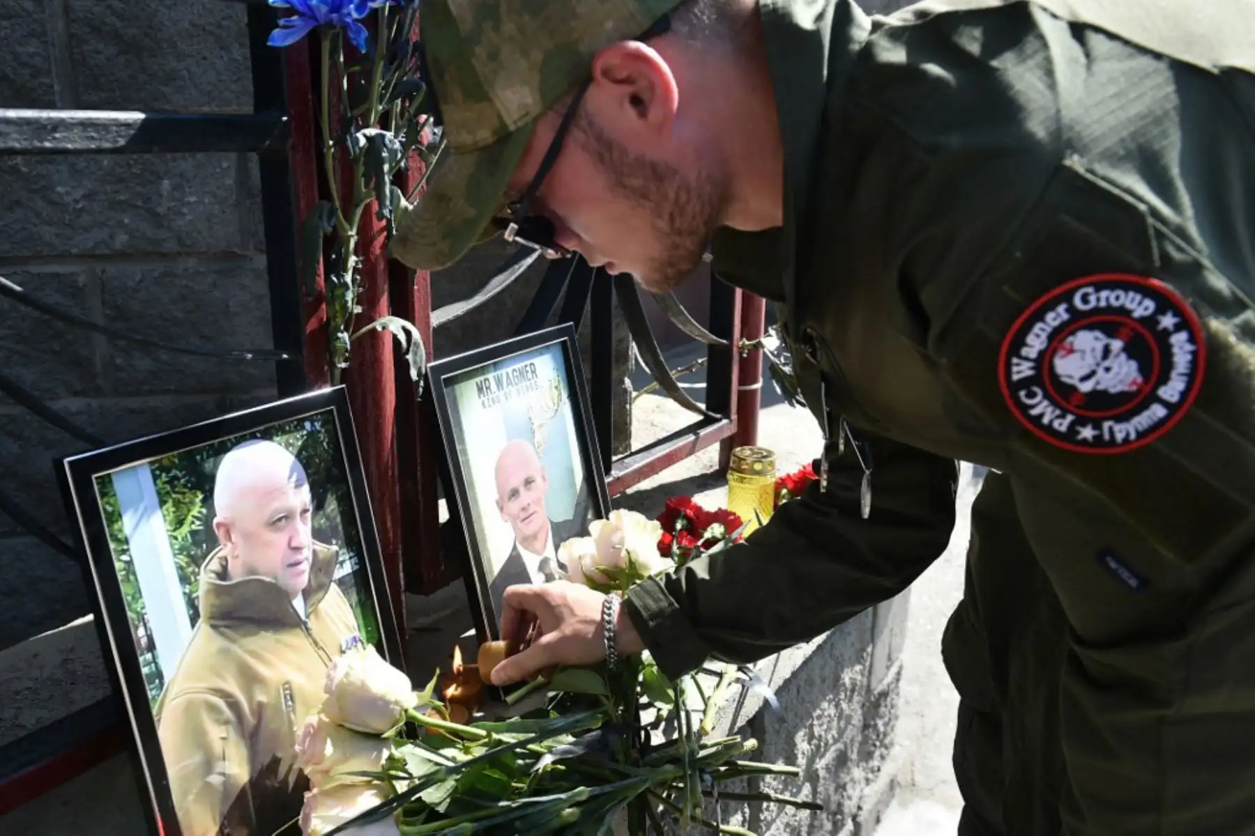 Un miembro del grupo mercenario privado Wagner rinde homenaje a Yevgeny Prigozhin y Dmitry Utkin, una figura oscura que dirigió las operaciones de Wagner y supuestamente sirvió en la inteligencia militar rusa, en el memorial improvisado frente a la oficina de PMC Wagner en Novosibirsk. Foto: AFP