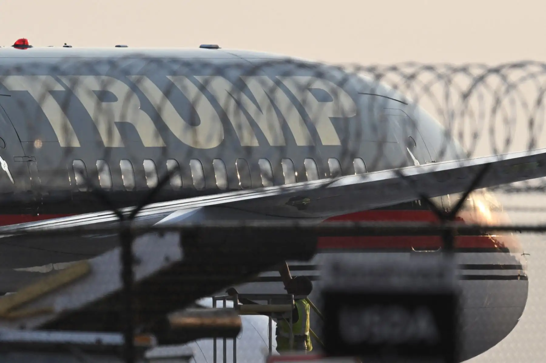 El avión Trump Force One del expresidente estadounidense Donald Trump es visto a través de alambre de púas a su llegada al Aeropuerto Internacional Hartsfield-Jackson en Atlanta, Georgia. El expresidente estadounidense Donald Trump se dirigió a Georgia.Trump, de 77 años, será fichado y puesto en libertad bajo fianza en la cárcel del condado de Fulton en Atlanta, acusado de confabularse con 18 coacusados para intentar anular el resultado de las elecciones de 2020 en el estado clave del sur. Foto:ANDINA/ AFP