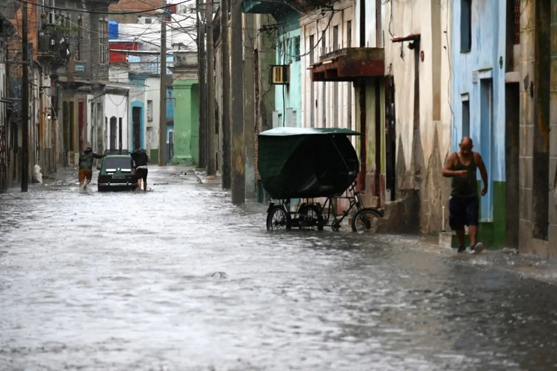 Personas transitan por una calle inundada en La Habana, durante el paso de la tormenta tropical Idalia. La tormenta tropical Idalia se fortaleció hasta convertirse en huracán este martes y los meteorólogos pronostican que se volverá "extremadamente peligrosa" antes de tocar tierra el miércoles en Florida, Estados Unidos. Foto: AFP
