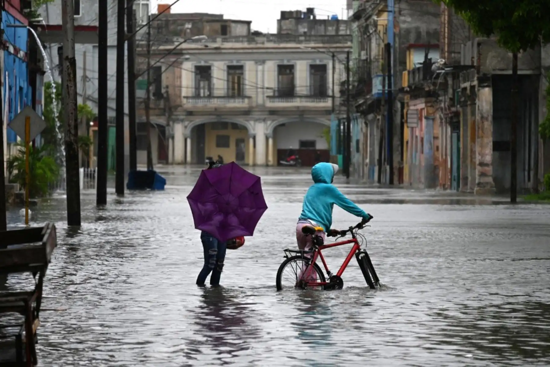 Personas transitan por una calle inundada en La Habana, durante el paso de la tormenta tropical Idalia. La tormenta tropical Idalia se fortaleció hasta convertirse en huracán este martes y los meteorólogos pronostican que se volverá "extremadamente peligrosa" antes de tocar tierra el miércoles en Florida, Estados Unidos. Foto: AFP