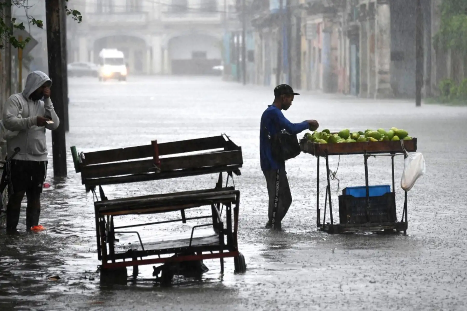 Cubanos caminan por una calle inundada en La Habana, durante el paso de la tormenta tropical Idalia. La tormenta tropical Idalia se fortaleció hasta convertirse en huracán este martes y los meteorólogos pronostican que se volverá "extremadamente peligrosa" antes de tocar tierra el miércoles en Florida, Estados Unidos. Foto: AFP