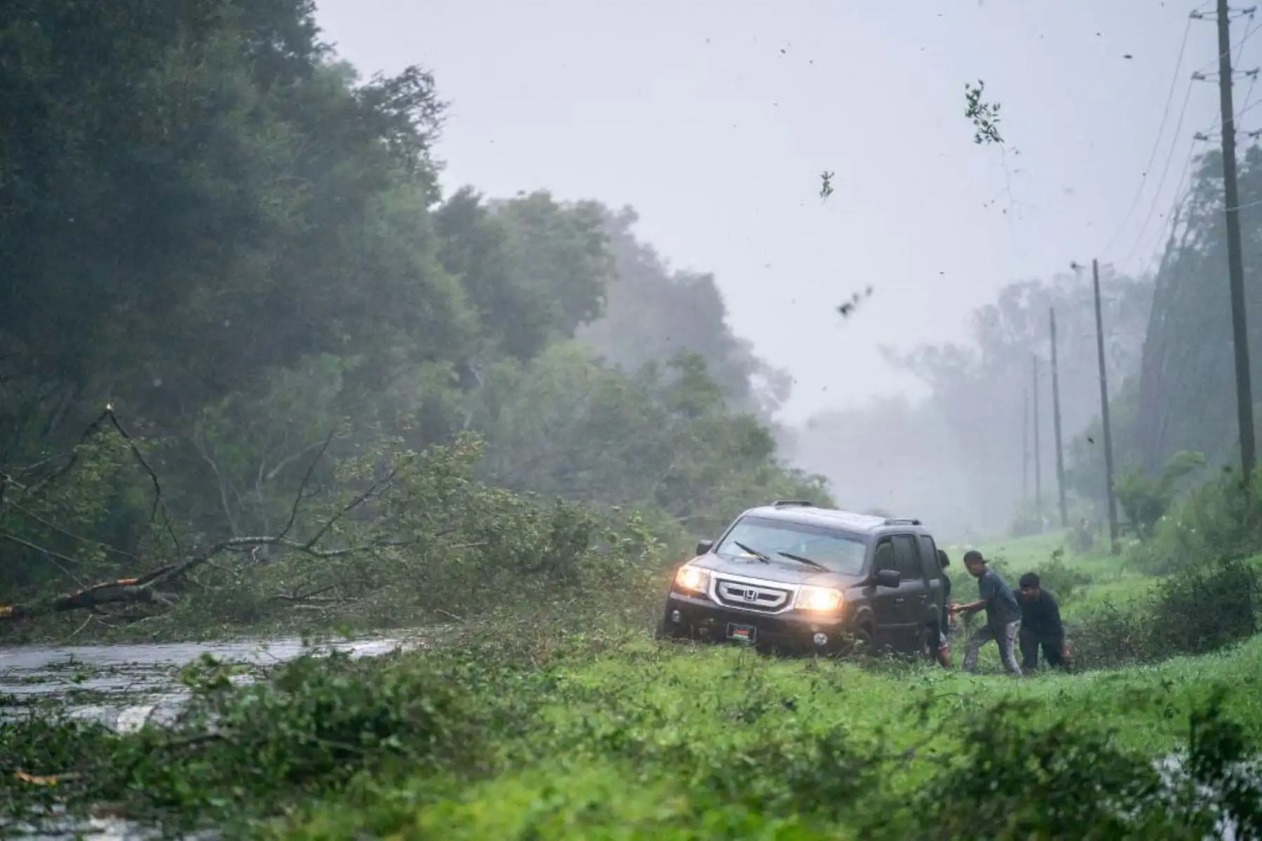 La gente trabaja para liberar un vehículo atrapado en el arcén entre los escombros de la tormenta mientras el huracán Idalia cruza el estado cerca de Mayo, Florida. La tormenta tocó tierra en Keaton Beach, Florida, como huracán de categoría 3. Foto: AFP