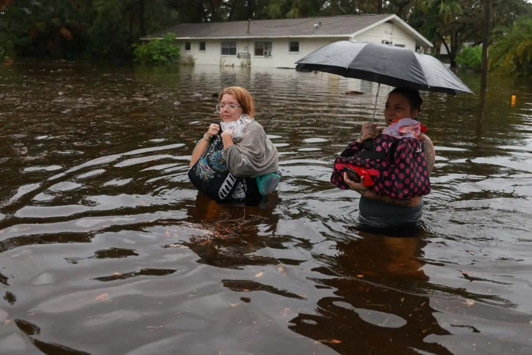 Makatla Ritchter y su madre, Keiphra Line, caminan a través de las aguas de la inundación después de tener que evacuar su casa cuando las aguas del huracán Idalia la inundaron en Tarpon Springs, Florida. El huracán Idalia está azotando el área de Big Bend en Florida. Foto: AFP