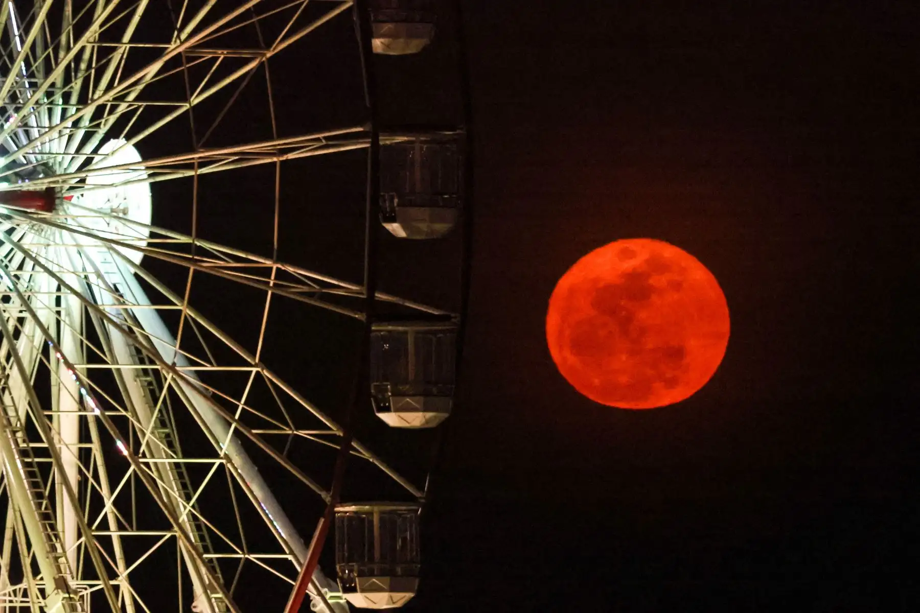 Una súper luna azul se eleva detrás de una noria ubicada en Stokes Hill Wharf, Australia,  en la ciudad capital del Territorio del Norte, Darwin, el 31 de agosto de 2023.Foto: AFP