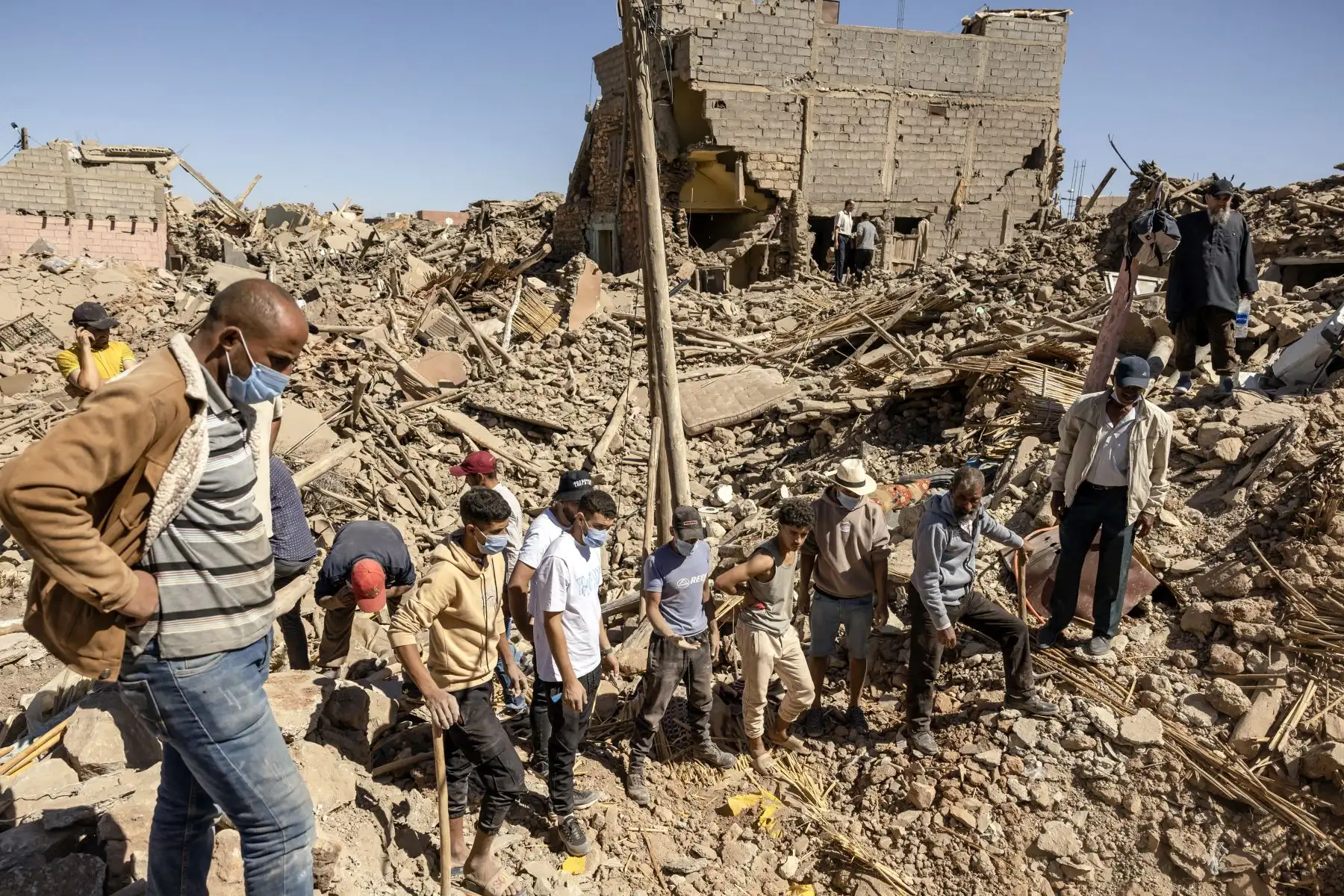 Los voluntarios observan cómo una excavadora mueve los escombros de las casas derrumbadas en Tafeghaghte, 60 kilómetros (37 millas) al suroeste de Marrakech, el 10 de septiembre de 2023, dos días después de que un devastador terremoto de magnitud 6,8 ​​sacudiera el país. El 10 de septiembre, los marroquíes lloraron a las víctimas de un devastador terremoto que mató a más de 2.000 personas mientras los equipos de rescate se apresuraban a encontrar sobrevivientes atrapados bajo los escombros de las aldeas arr