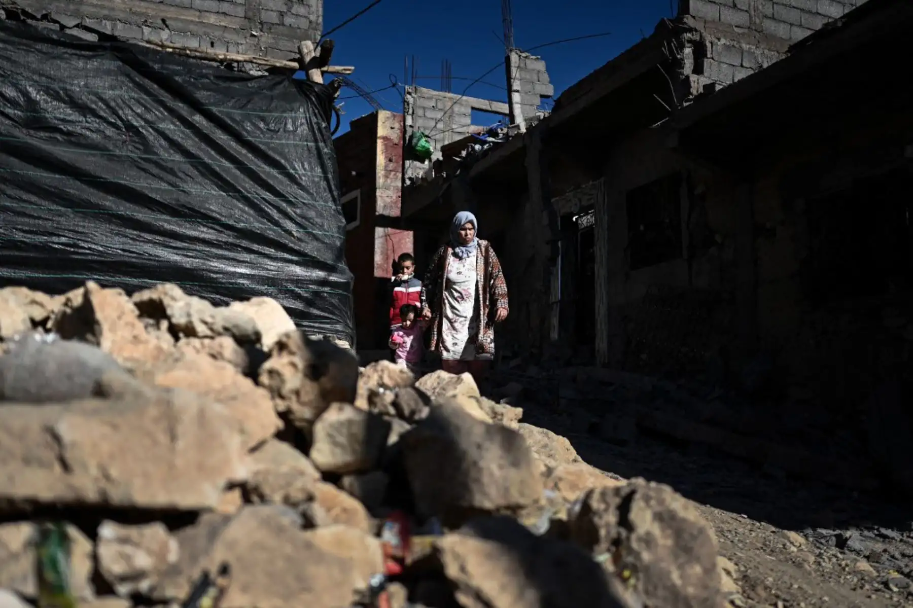 Una mujer y sus hijos, pasan junto a casas destruidas en el pueblo de montaña de Moulay Brahim. Foto: AFP