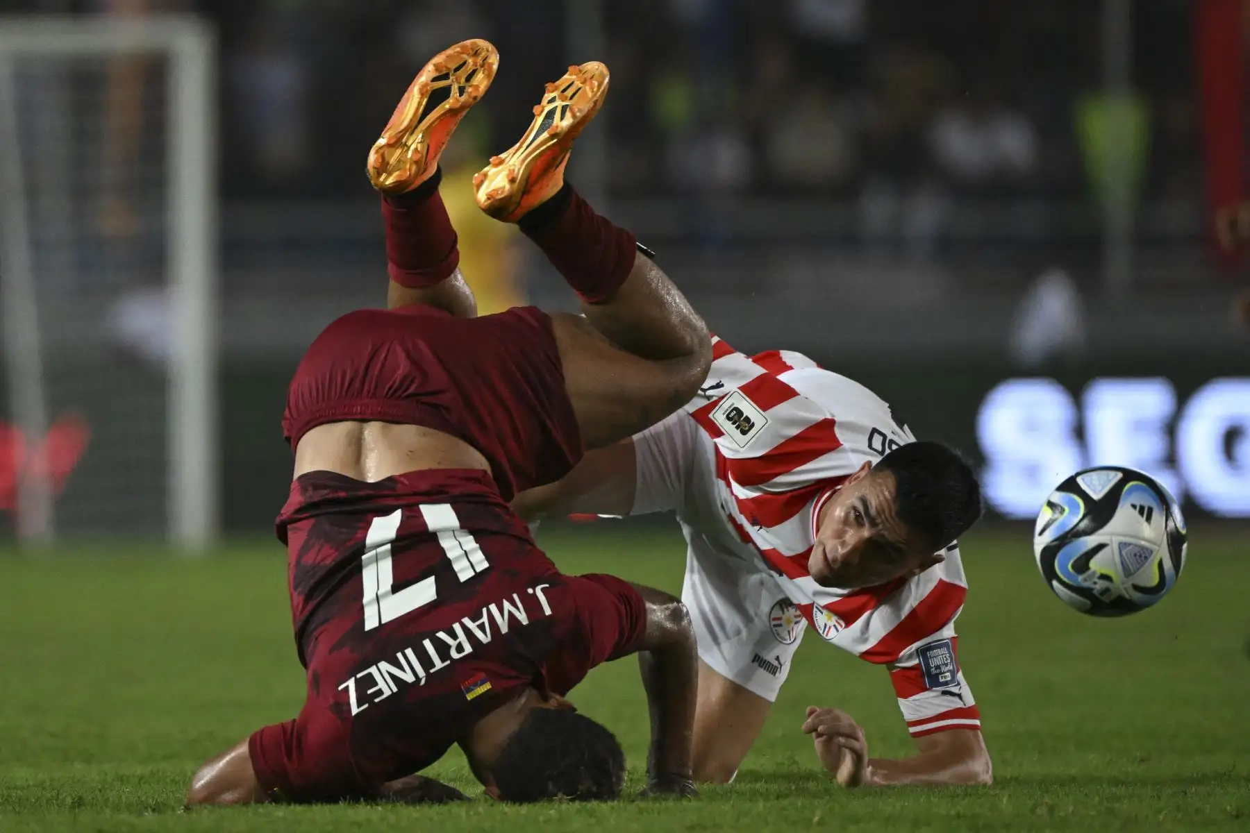 El delantero venezolano Josef Martínez y el mediocampista paraguayo Matías Rojas caen durante el partido de fútbol de las eliminatorias sudamericanas para la Copa Mundial de la FIFA 2026 entre Venezuela y Paraguay, en el estadio Monumental de Maturín, Venezuela, el 12 de septiembre de 2023.
Foto: AFP