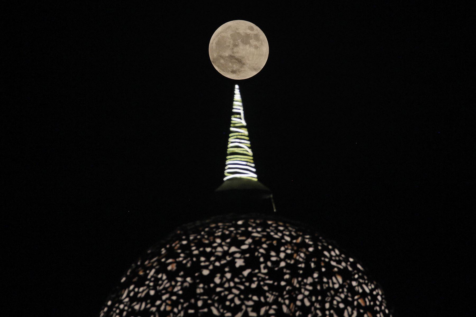 La luna llena se eleva sobre la cúpula de una galería comercial en las afueras de Nueva Delhi el 29 de septiembre de 2023. 
Foto: AFP