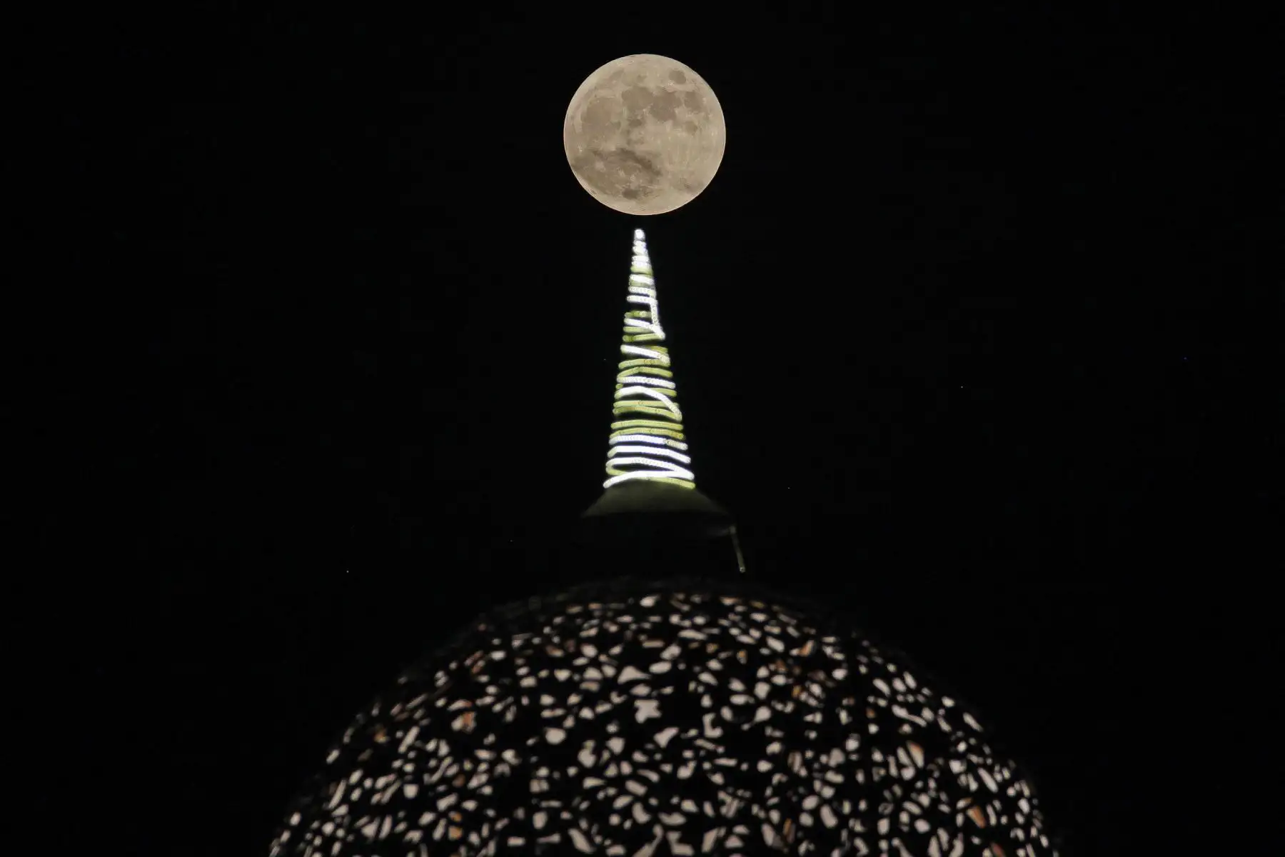 La luna llena se eleva sobre la cúpula de una galería comercial en las afueras de Nueva Delhi el 29 de septiembre de 2023. 
Foto: AFP