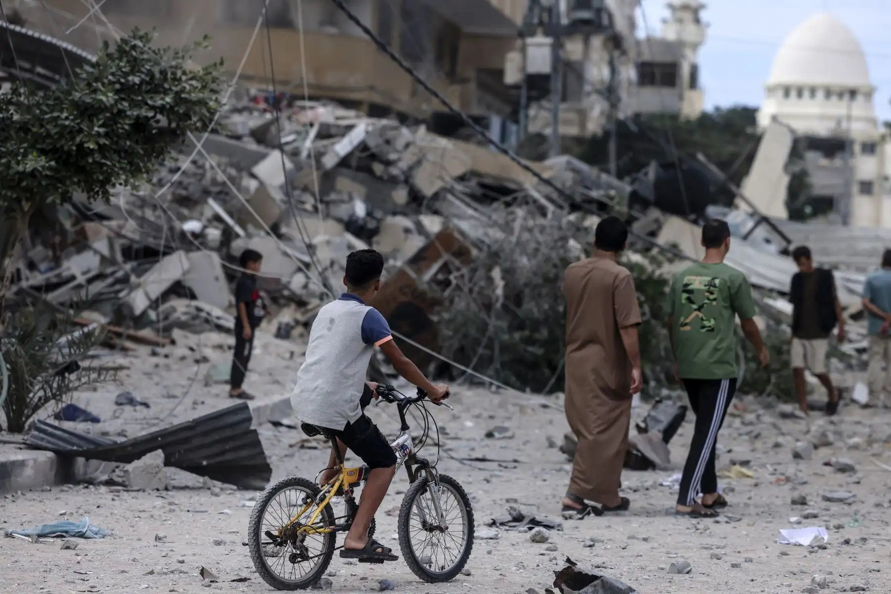 Un joven pasa en bicicleta por un edificio destruido por los ataques aéreos israelíes en la ciudad de Gaza el 7 de octubre de 2023. Los militantes palestinos han comenzado una "guerra" contra Israel, en la que se infiltraron por aire, mar y tierra desde el La bloqueada Franja de Gaza, dijeron funcionarios israelíes, constituye una importante escalada en el conflicto palestino-israelí. Foto. ANDINA/ AFP