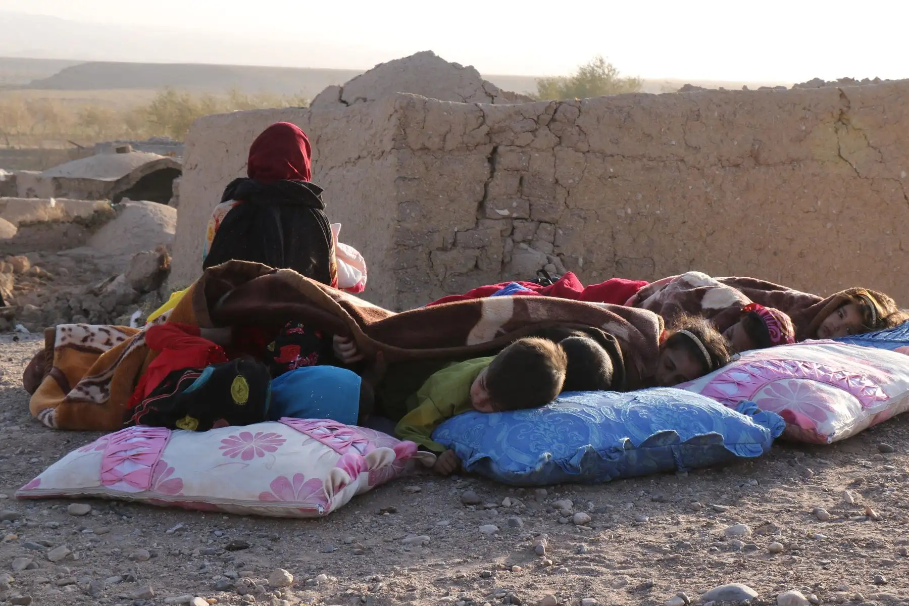 Niños afganos descansan bajo una manta junto a casas dañadas después del terremoto en la aldea de Sarbuland del distrito de Zendeh Jan de la provincia de Herat.
Foto: AFP