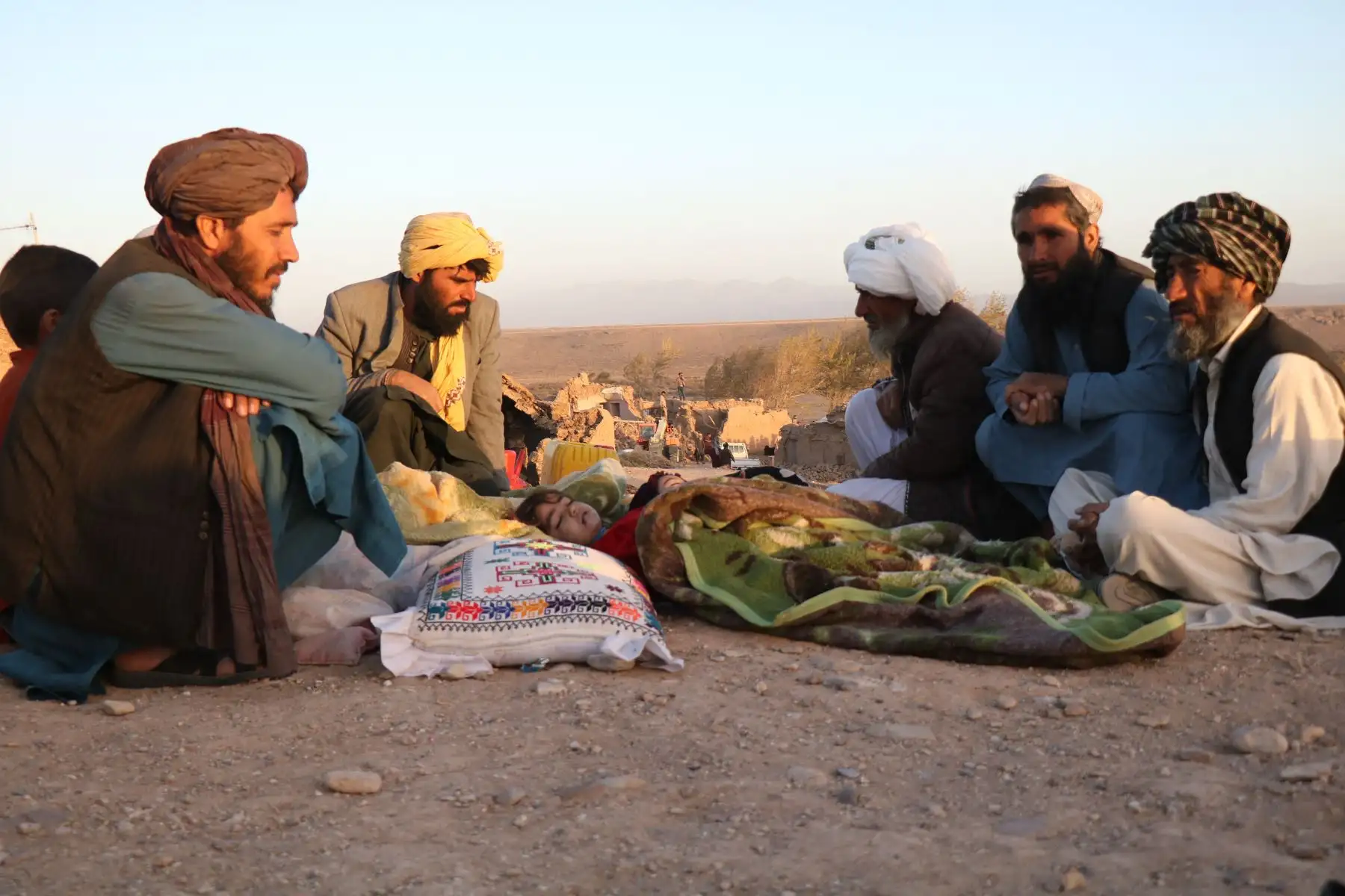 Hombres afganos sentados junto a los cuerpos de sus familiares muertos tras un terremoto en la aldea de Sarbuland, distrito de Zendeh Jan, provincia de Herat.
Foto: AFP