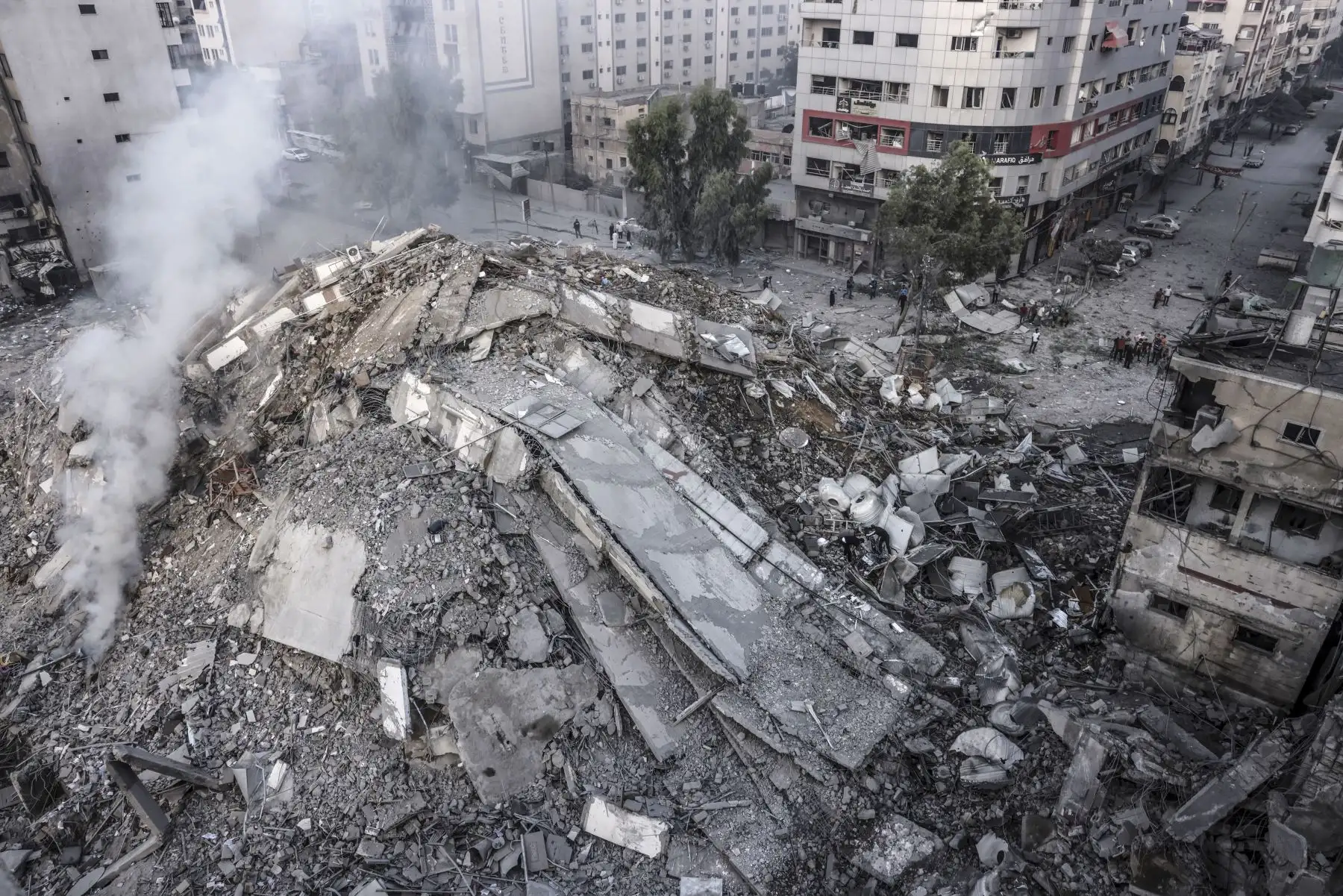 La gente camina alrededor de las ruinas de un edificio destruido en los ataques aéreos israelíes en la ciudad de Gaza 
Foto: AFP