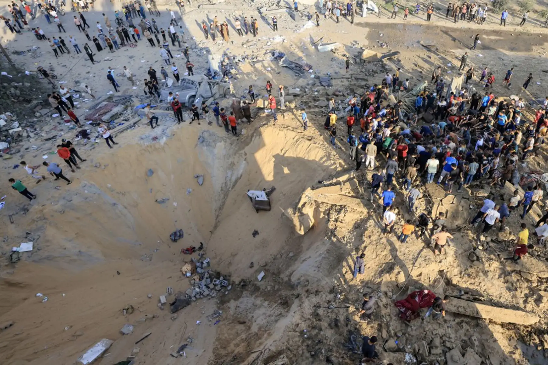 Los palestinos se encuentran junto a un cráter causado por una explosión de un ataque aéreo israelí en Khan Yunis, en el sur de la Franja de Gaza.
Foto: AFP