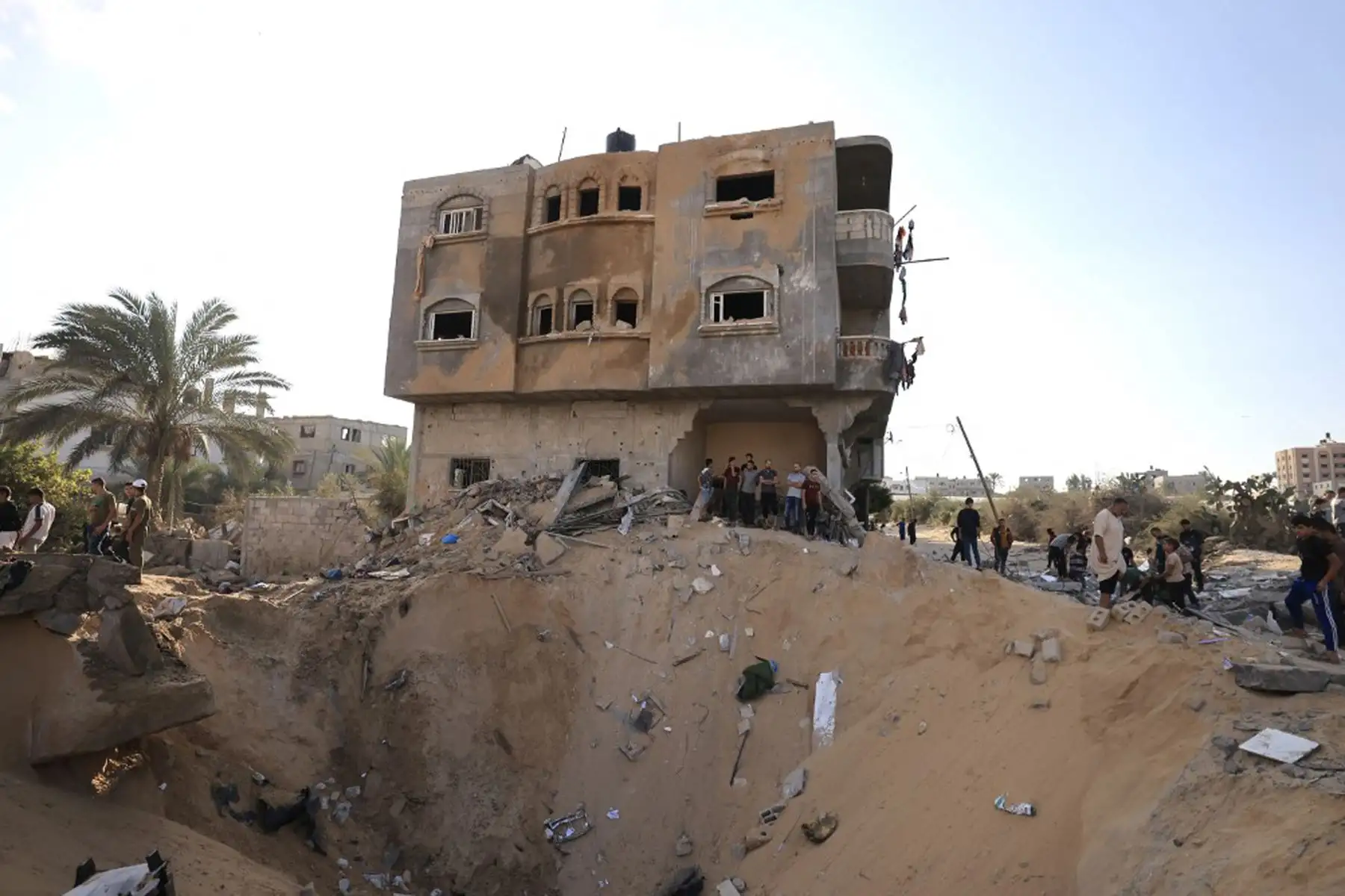 Los palestinos se encuentran junto a un cráter causado por una explosión de un ataque aéreo israelí en Khan Yunis, en el sur de la Franja de Gaza.
Foto: AFP