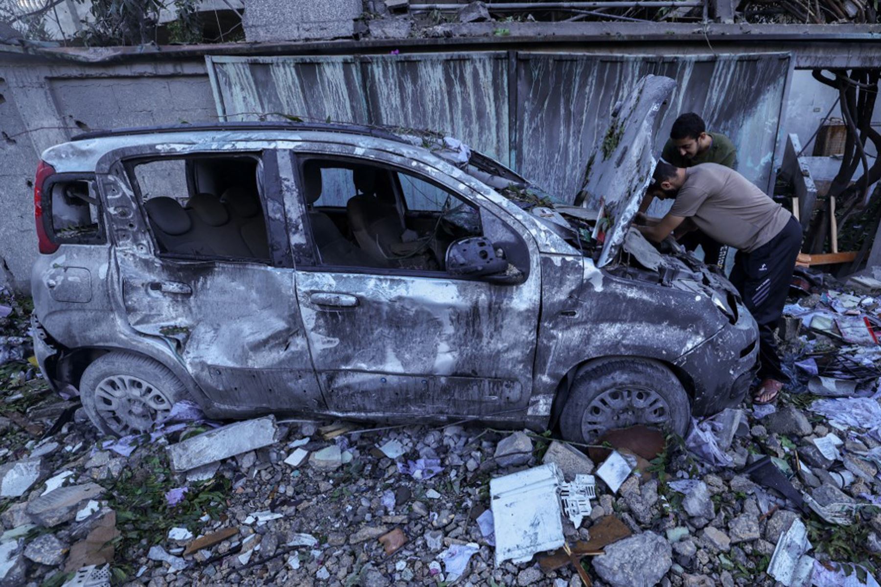 Los palestinos inspeccionan su automóvil destruido después de un ataque aéreo israelí en el campo de refugiados de Rafah, en el sur de la Franja de Gaza.
Foto: AFP
