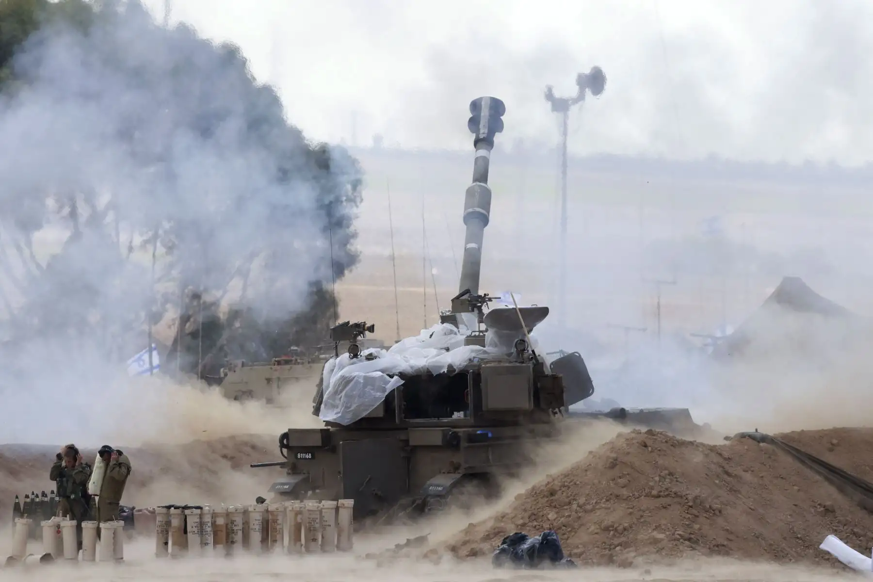 Soldados israelíes se tapan los oídos mientras un obús autopropulsado M109 de 155 mm dispara balas desde cerca de la frontera israelí con Gaza en el sur de Israel.
Foto: AFP