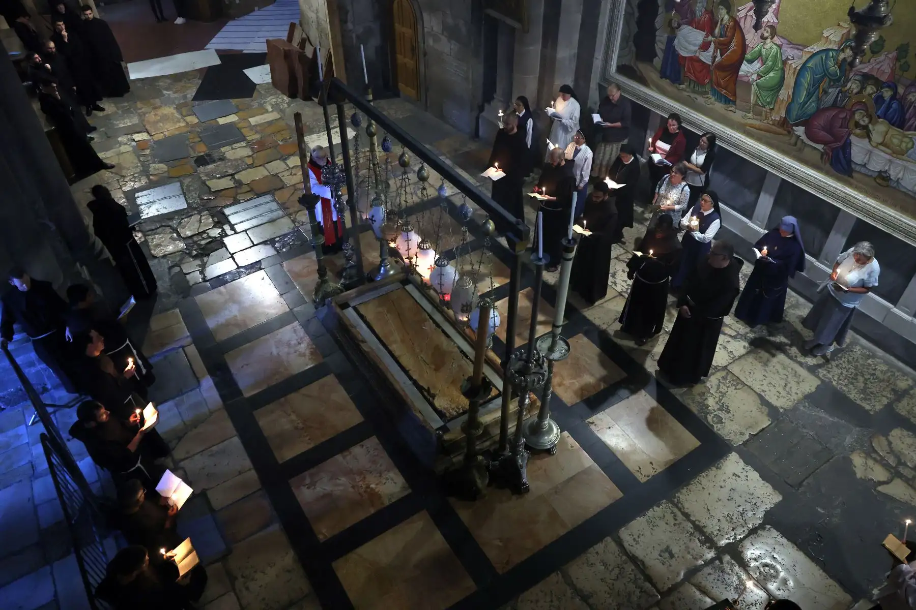 Frailes franciscanos y fieles rezan alrededor de la piedra de la Unción durante una procesión dedicada a la paz en Israel y Gaza, en la Iglesia del Santo Sepulcro en la Ciudad Vieja de Jerusalén, 
Foto: AFP