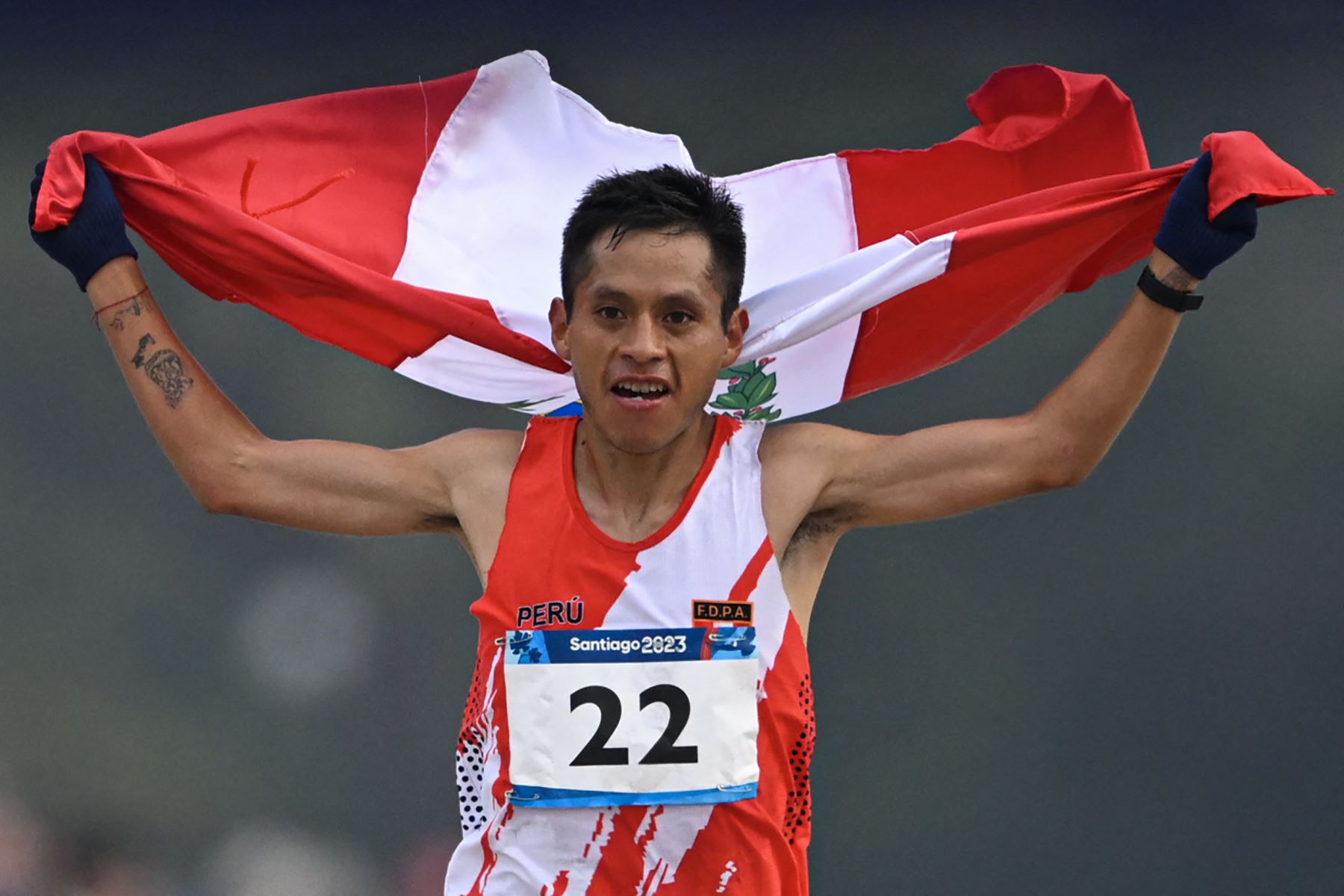 Cristhian Simeón Pacheco Mendoza de Perú muestra su bandera nacional luego de cruzar la línea de meta en primer lugar durante la final del maratón masculino de los Juegos Panamericanos Santiago 2023, en el Estadio Nacional, en Santiago.Foto: AFP