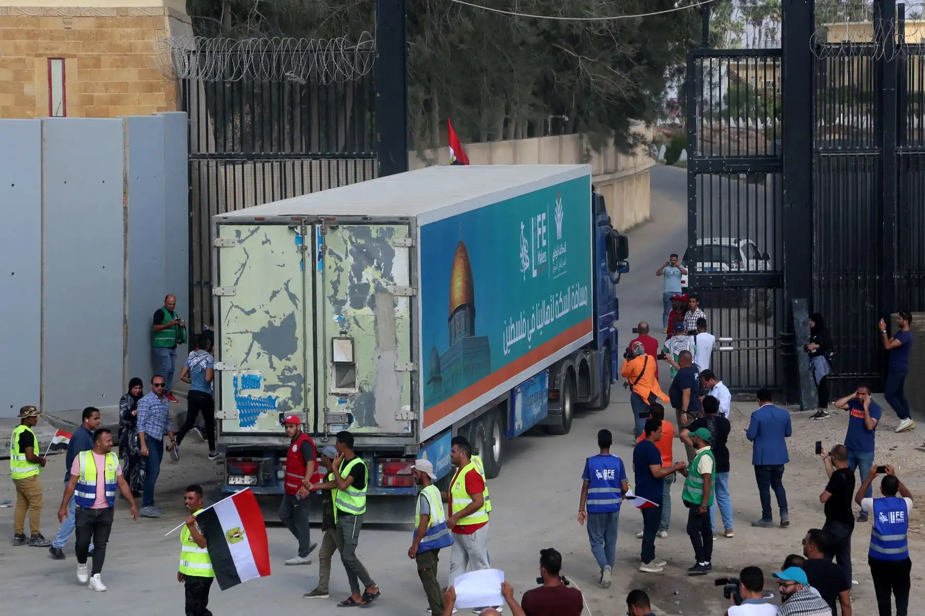 La gente en el lado egipcio del cruce fronterizo de Rafah observa cómo un convoy de camiones que transportan ayuda humanitaria cruza hacia la Franja de Gaza.
Foto: AFP