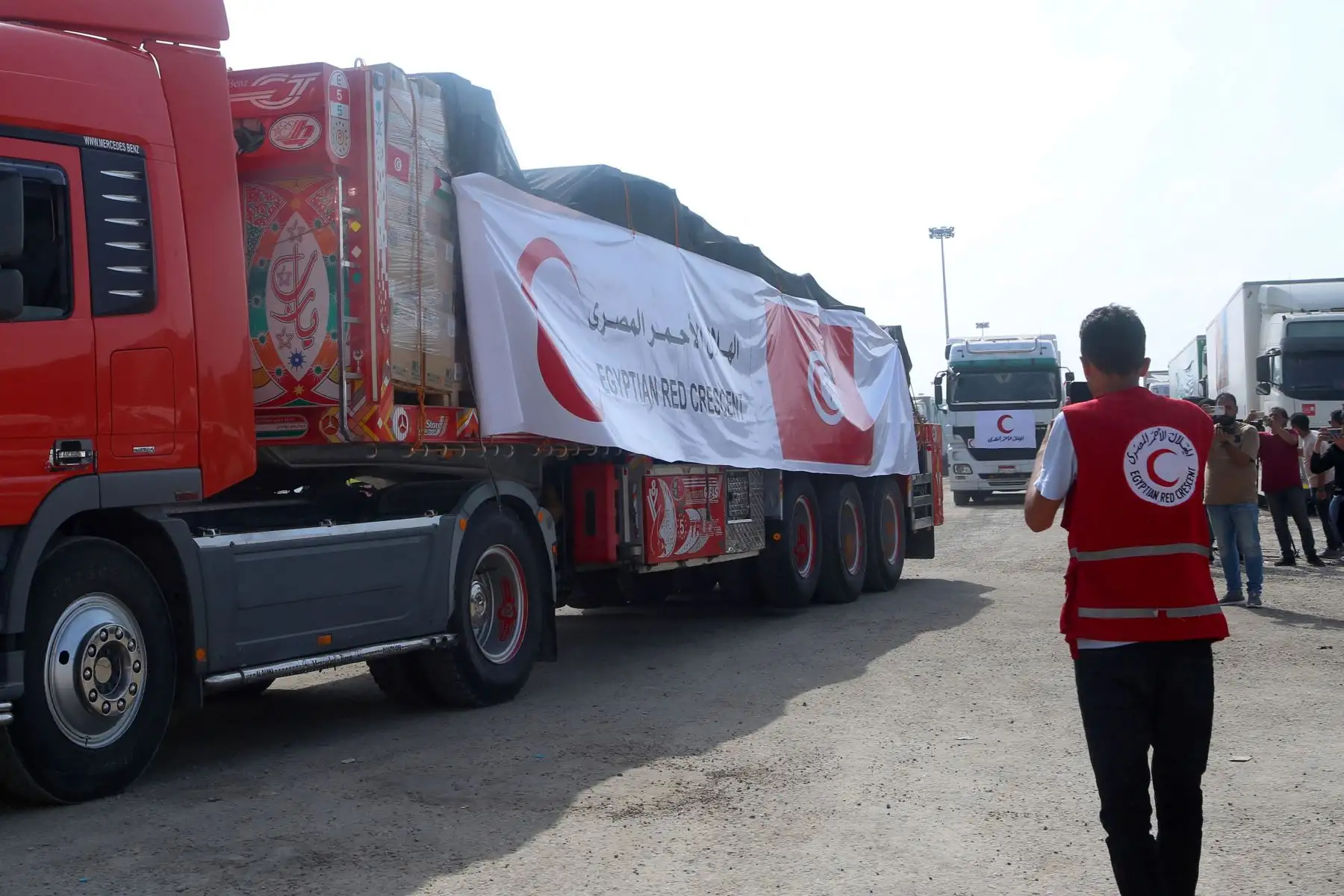 Un voluntario de la Media Luna Roja Egipcia observa cómo un convoy de camiones que transportan ayuda humanitaria cruza hacia la Franja de Gaza.
Foto: AFP