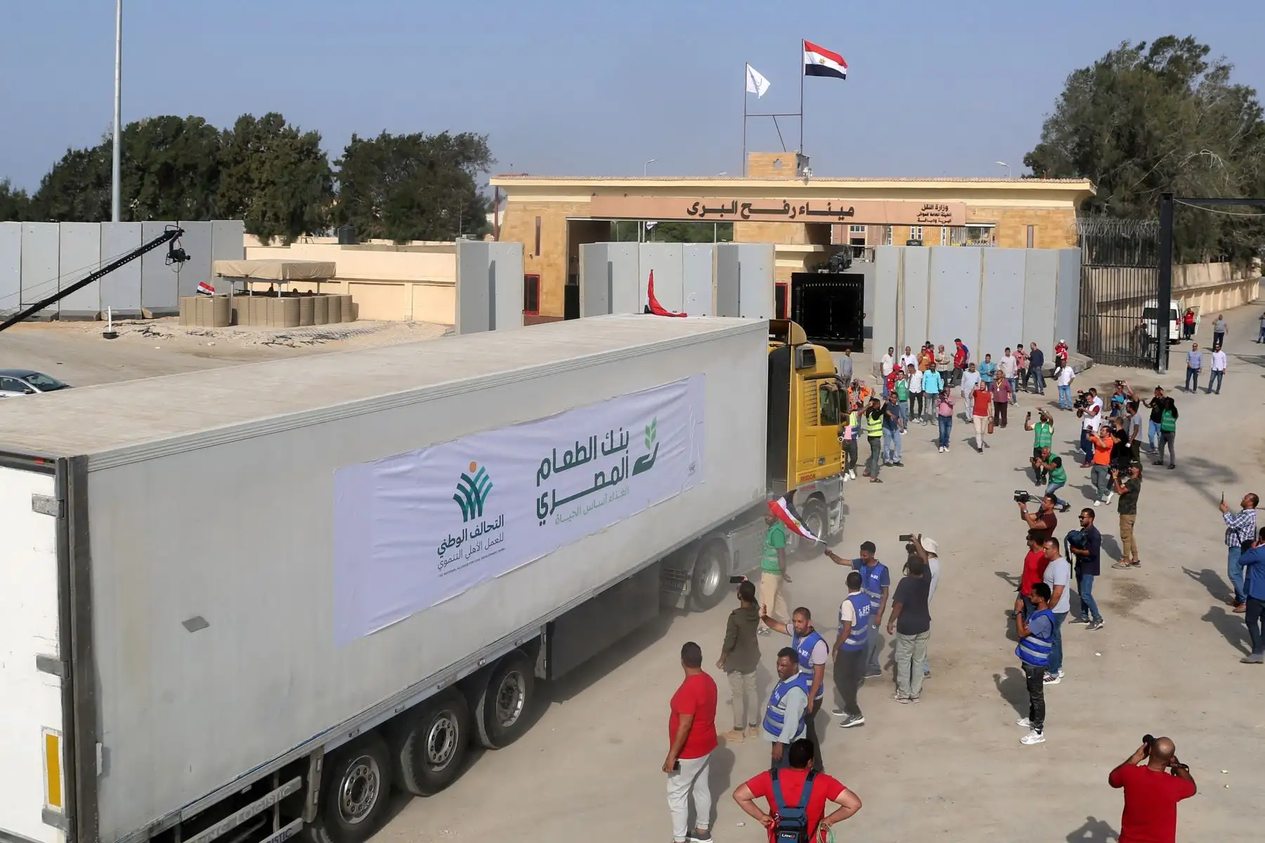 La gente en el lado egipcio del cruce fronterizo de Rafah observa cómo un convoy de camiones que transportan ayuda humanitaria cruza hacia la Franja de Gaza.
Foto: AFP