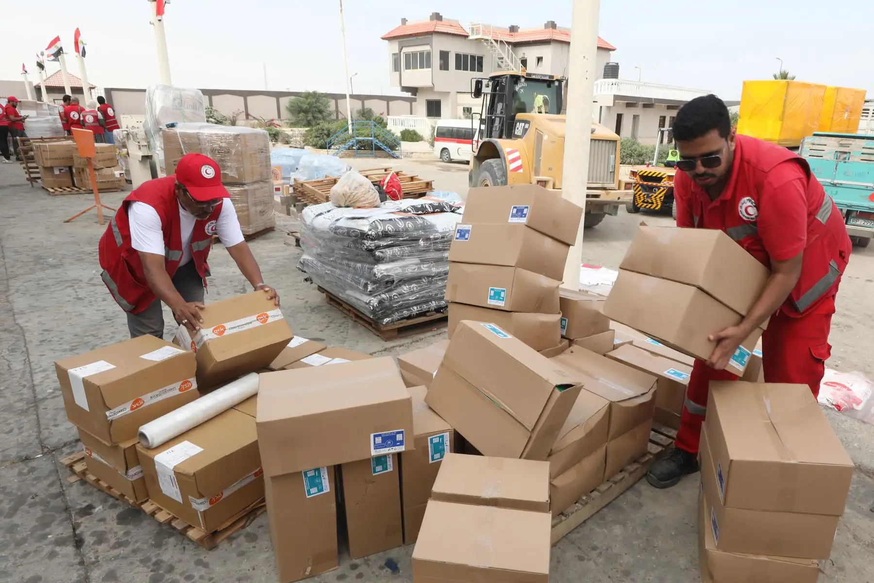 Empleados de la Sociedad de la Media Luna Roja Egipcia manejan ayuda humanitaria con destino a los palestinos en la Franja de Gaza, en un almacén en Arish, Egipto,  palestinos y al menos 1.300 israelíes han muerto, según las Fuerzas de Defensa de Israel (FDI) y las autoridades sanitarias palestinas, desde que militantes de Hamás lanzaron un ataque contra Israel. Foto: ANDINA/ EFE