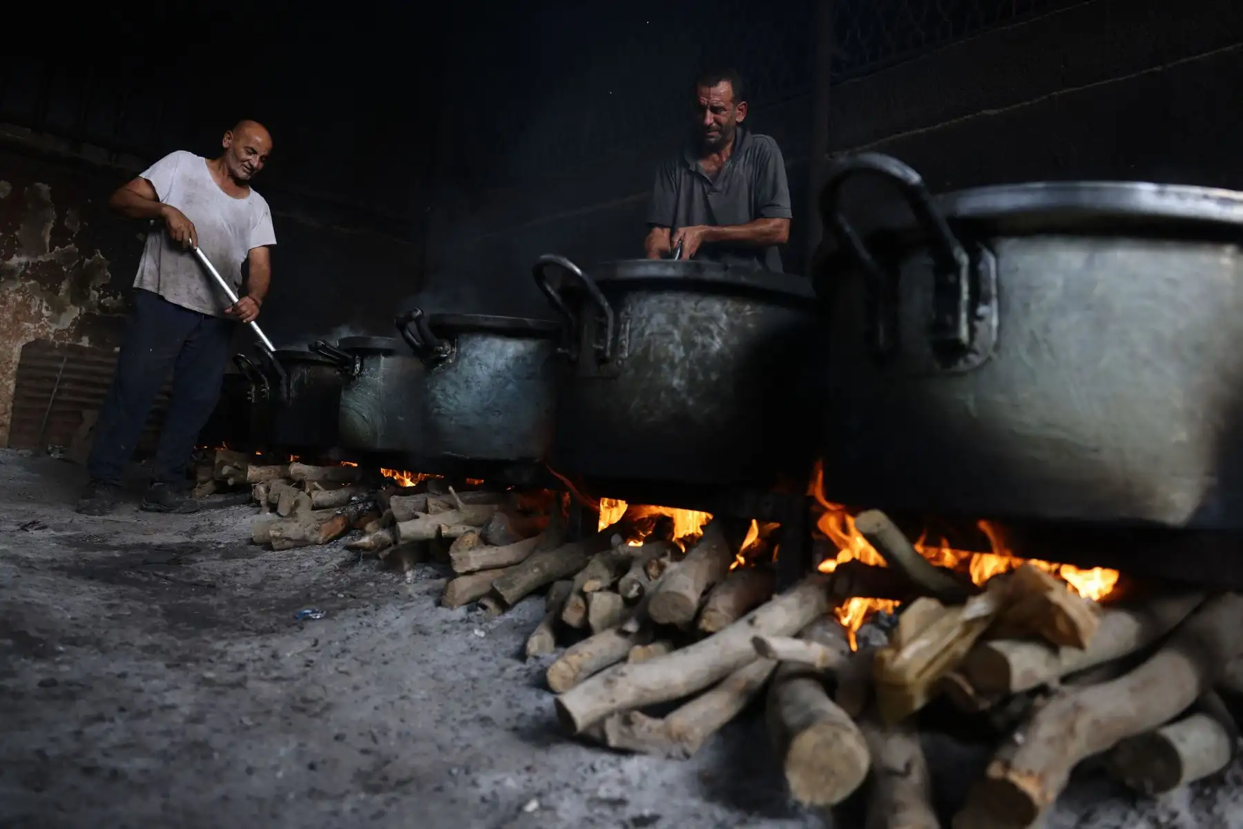 Hombres palestinos preparan comida en grandes ollas que hierven a fuego lento sobre fuegos de madera debido a la falta de gas para cocinar, que se distribuirá a las familias desplazadas tras el llamamiento de Israel para que más de 1 millón de residentes en el norte de Gaza se trasladen al sur, en Rafah, en el sur de la Franja de Gaza. Foto: ANDINA/AFP